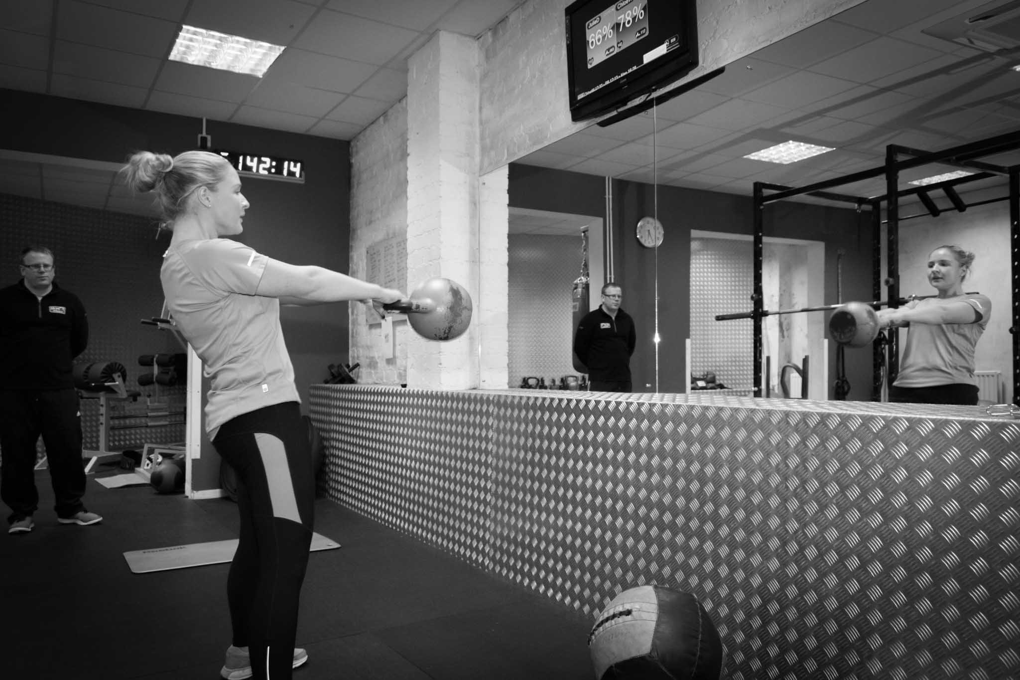 Commercial photo for a gym in Portadown as member exercises looking into the mirror as personal trainer watches.