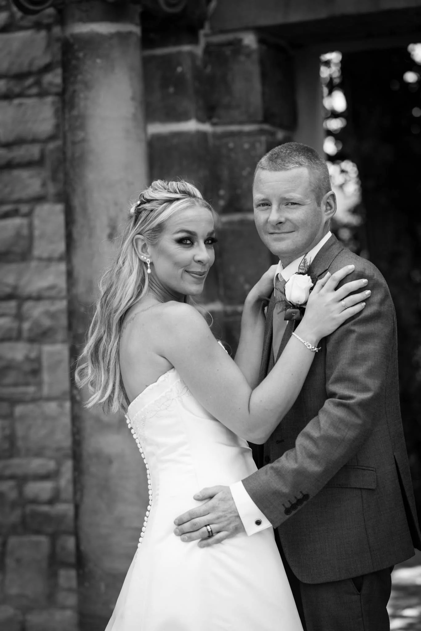 A portrait of a couple embracing each other as they look at Philip Topping's camera in mono black and white.