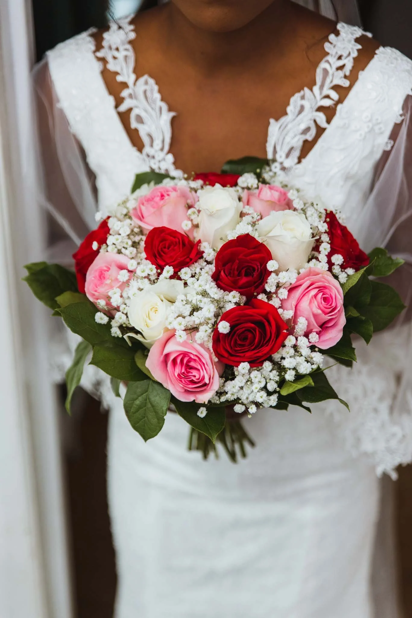 Close up of a coloured bride holds bouquet in the hallway.
