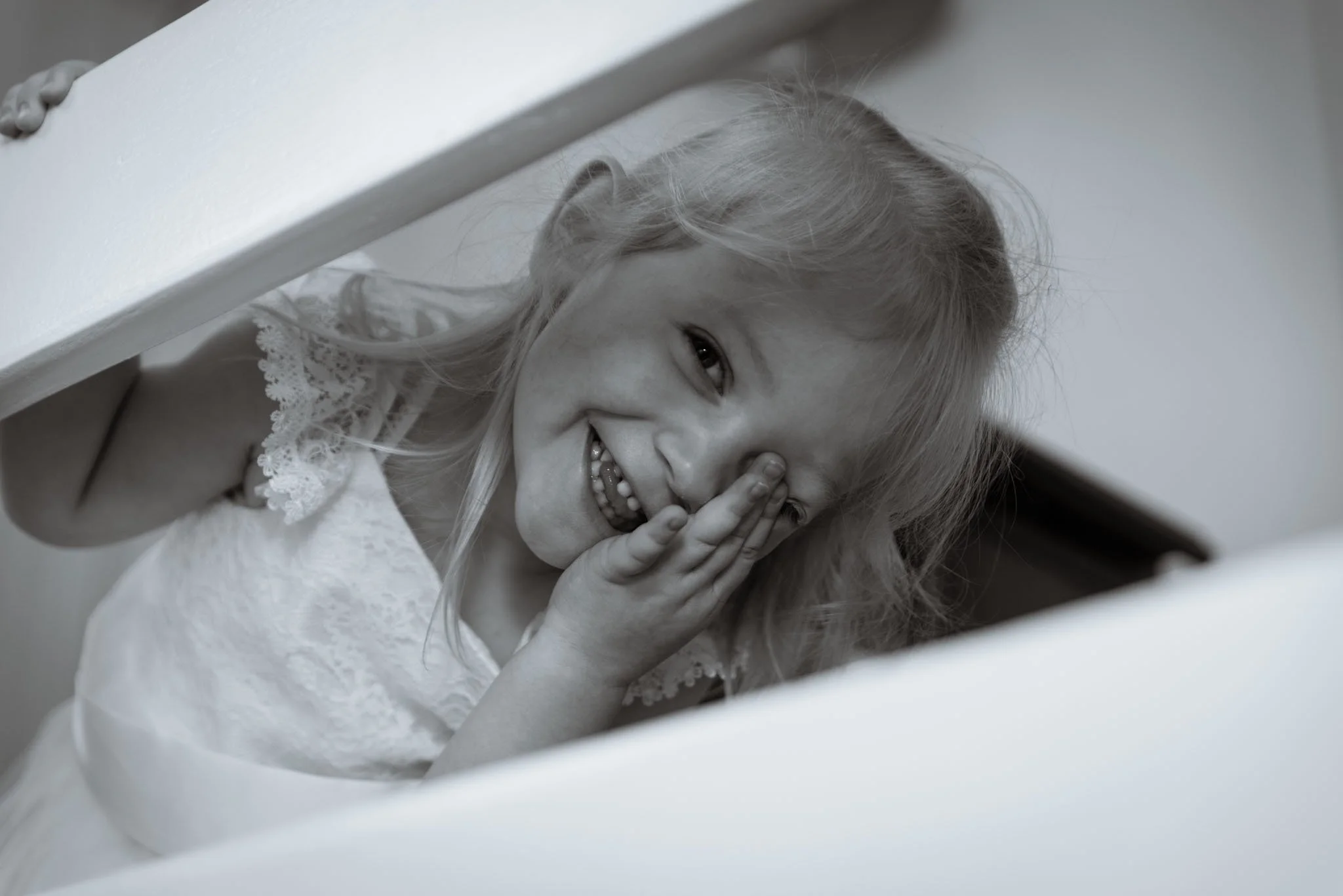 Young girl peeing through the staircase bannister in black and white.