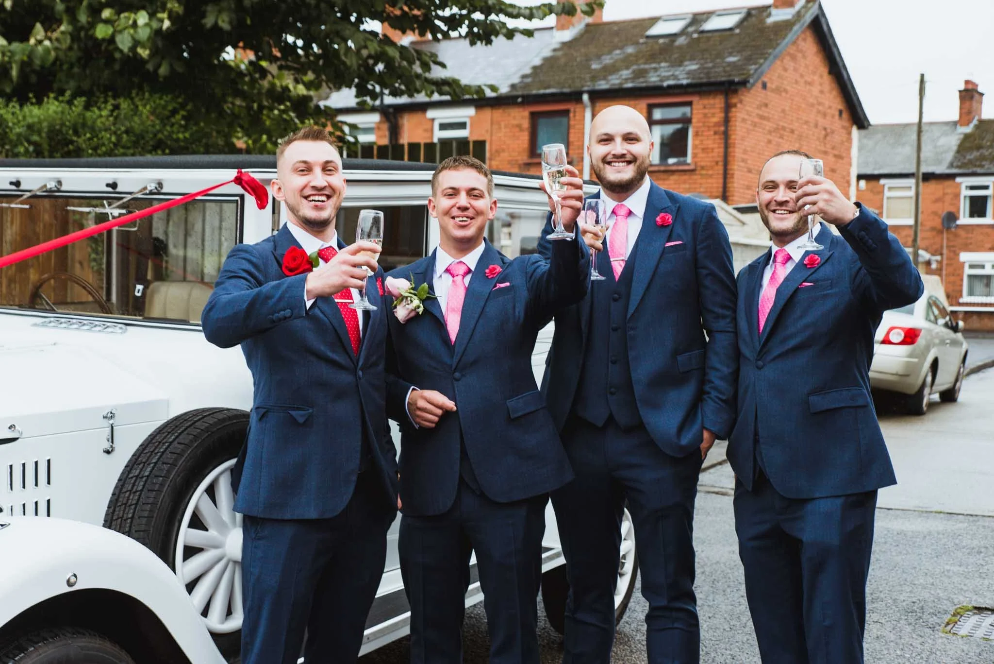 Groom with groomsmen beside the limo toasting to the day outside on the street.