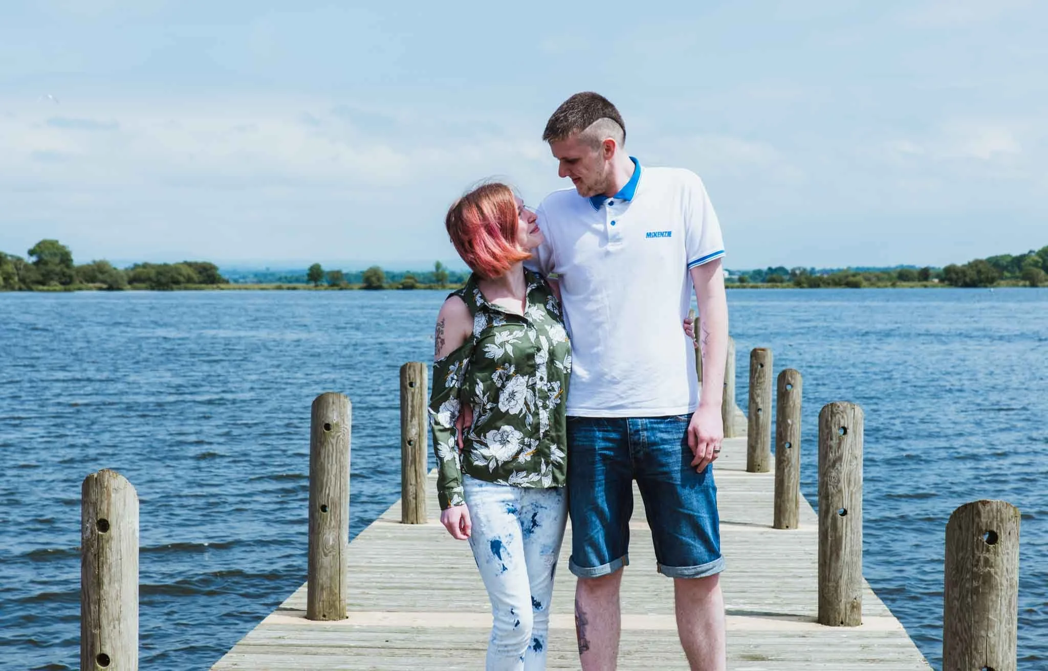 The couple at the jetty is looking into each other's eyes.