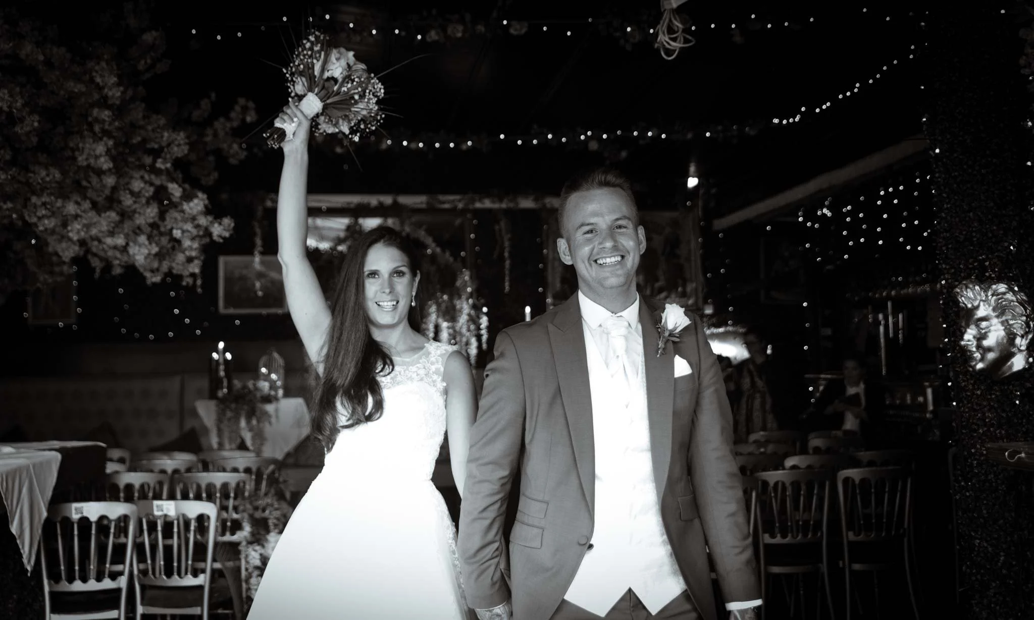 Mono image of the bride and groom walking down the aisle, smiling.