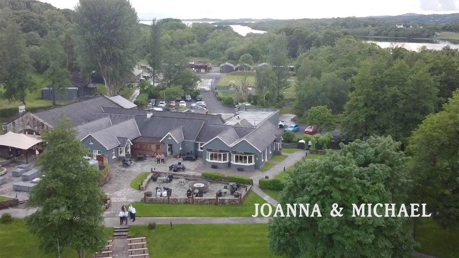 Bird's-eye view looking down on the venue with guests outside at benches at a wedding.