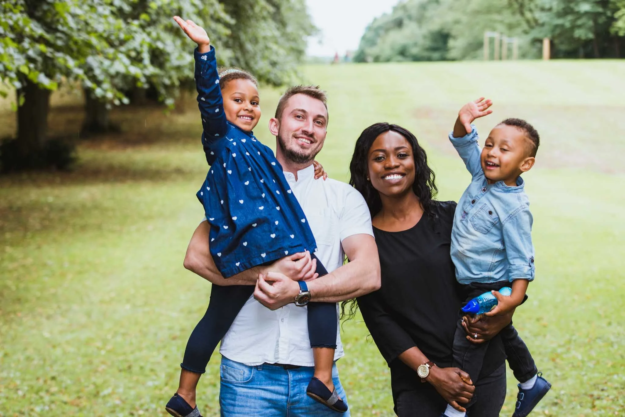 Parents holding kids waving.