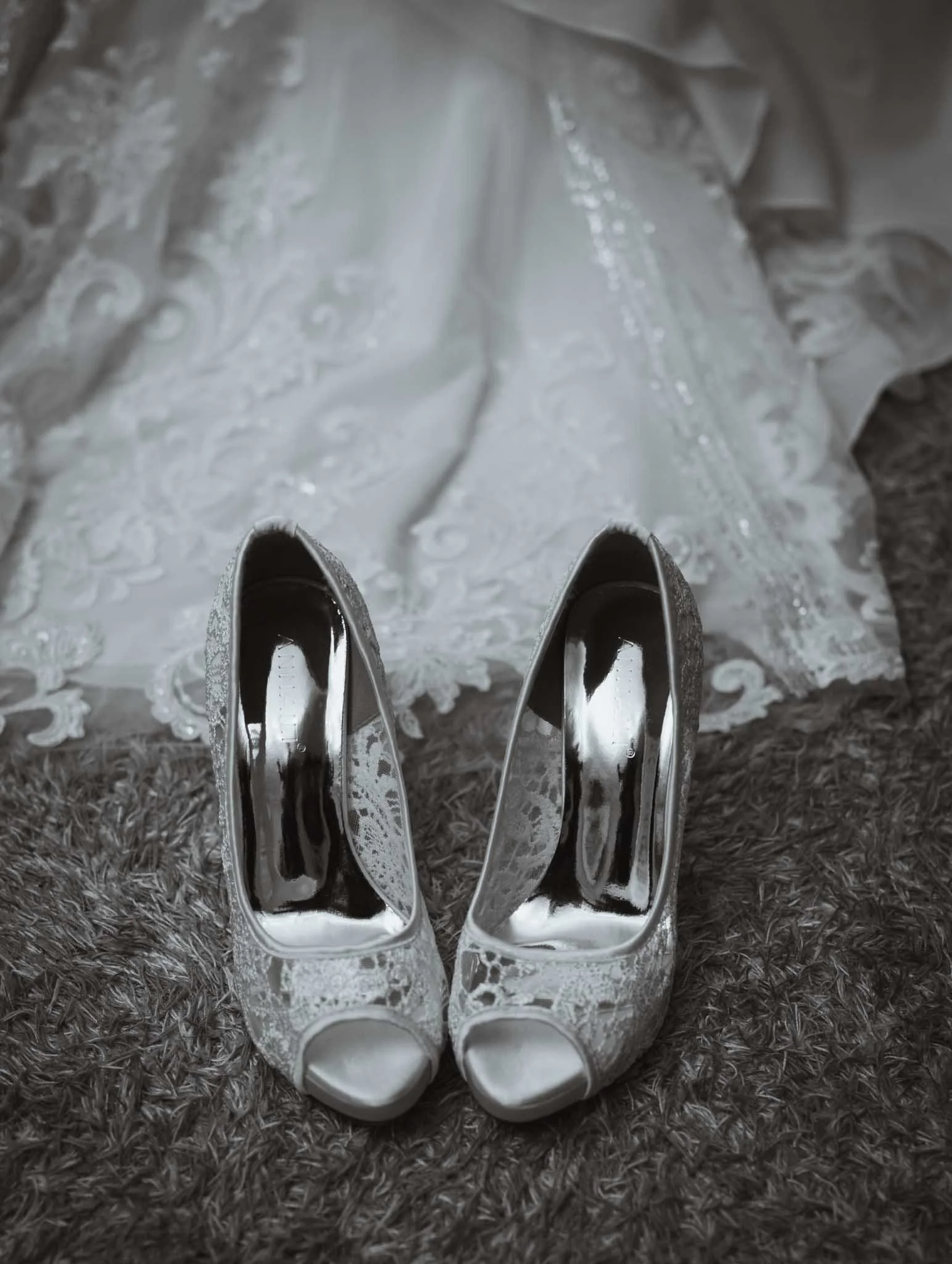 Brides shoes beside the dress on the carpet.