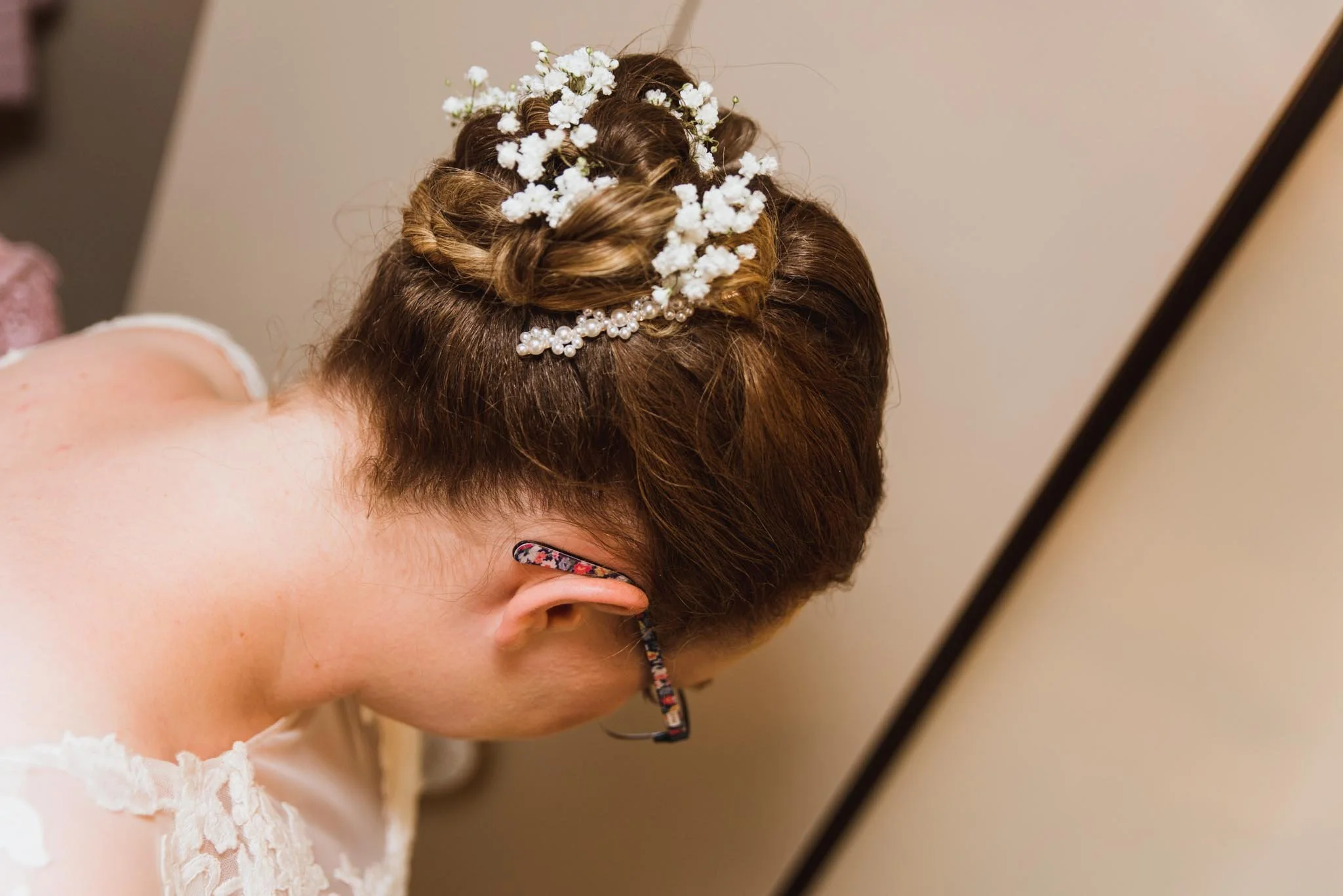 Brides head with a headpiece on in bedroom.