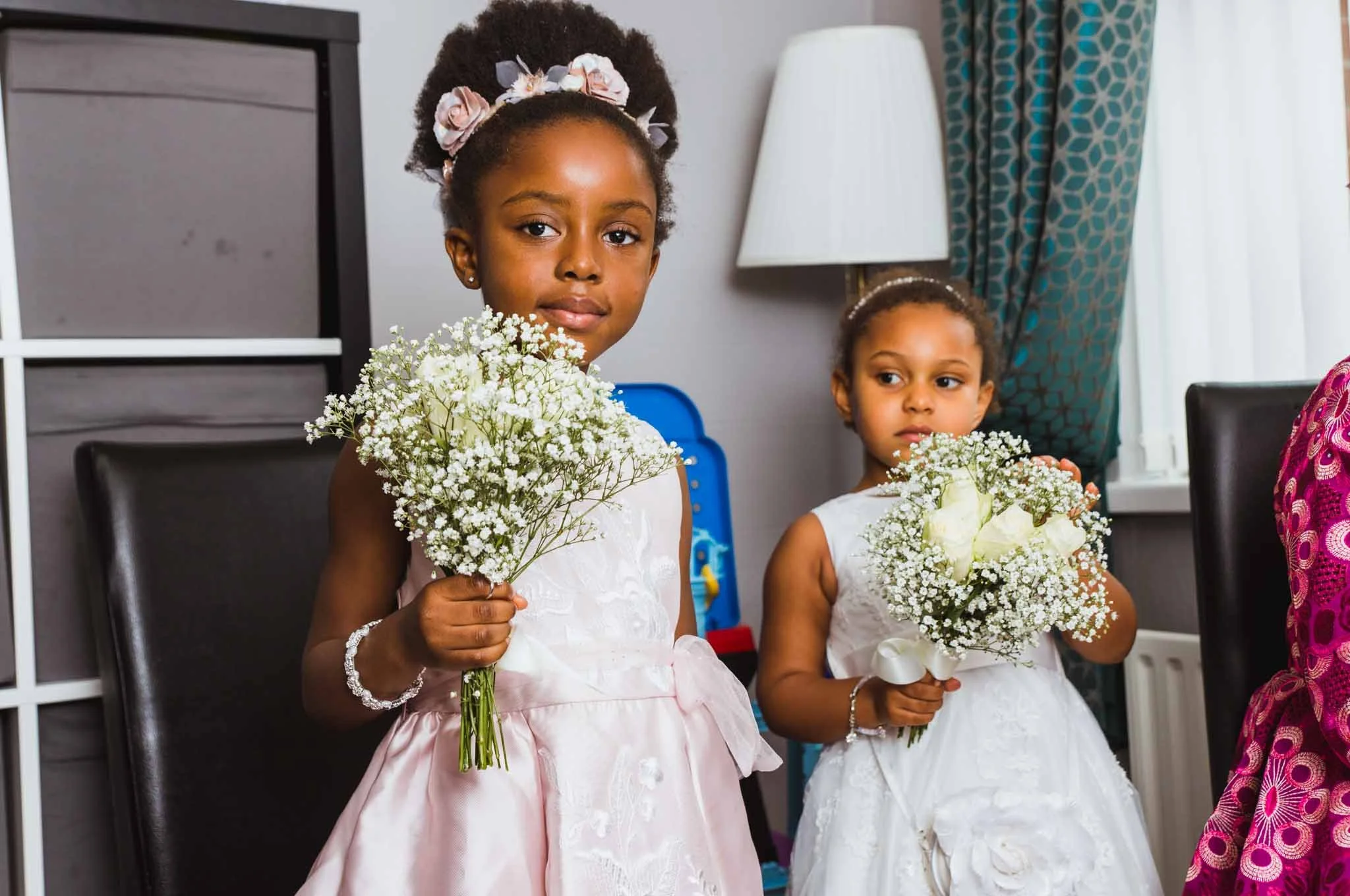 Young kids holding bouquets in the living room.