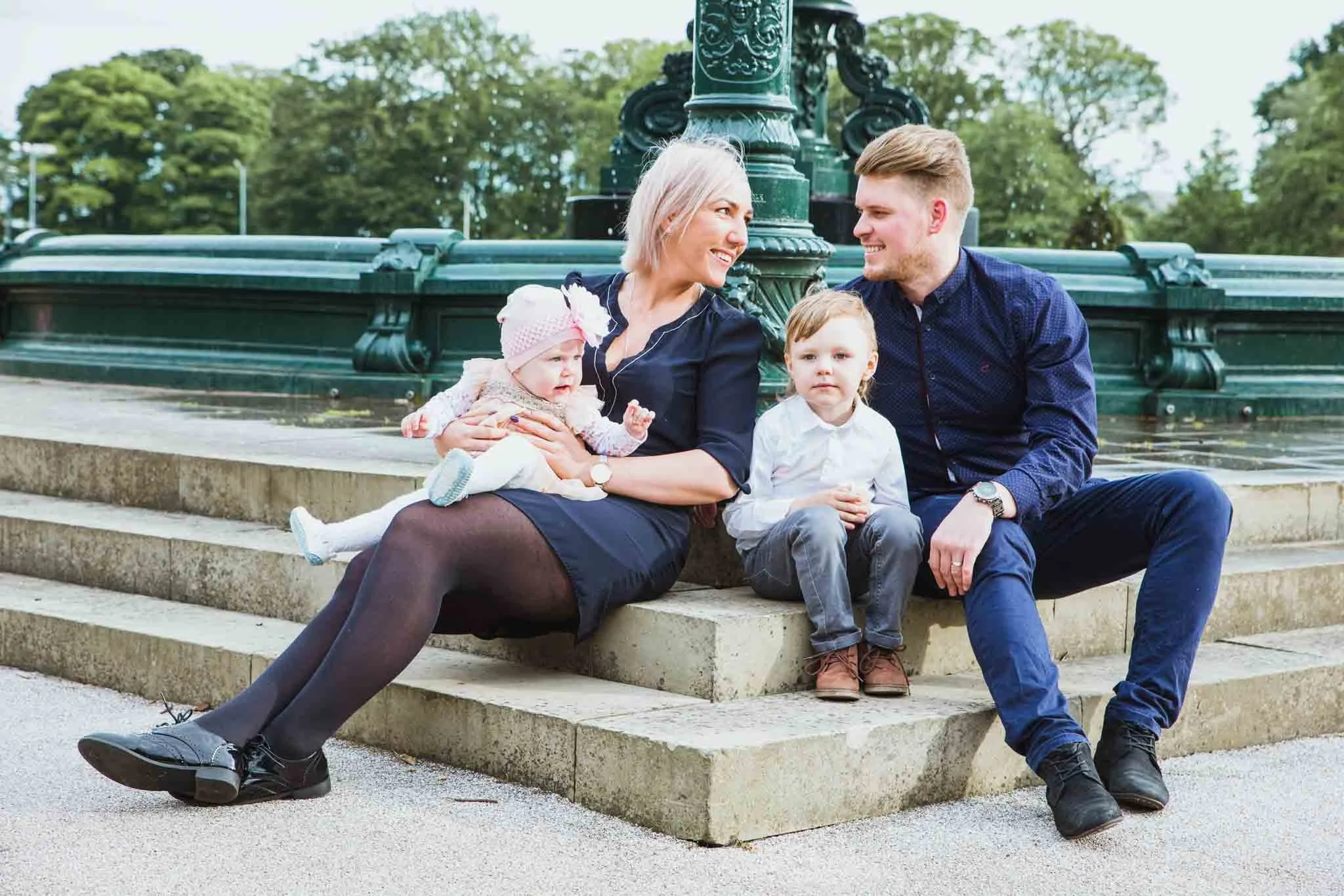 The family is sitting at the fountain, smiling.
