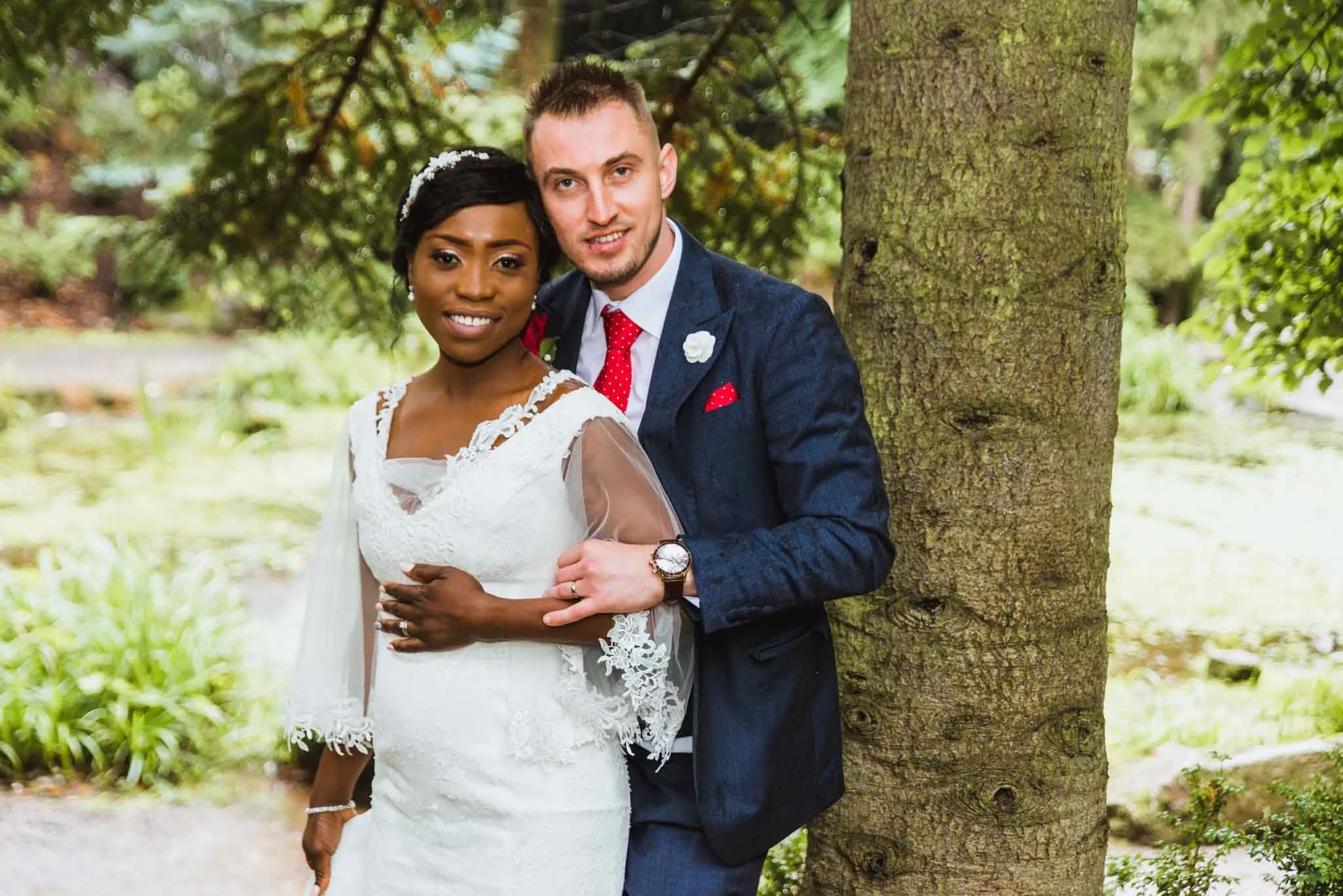 A male holding a female beside a tree.