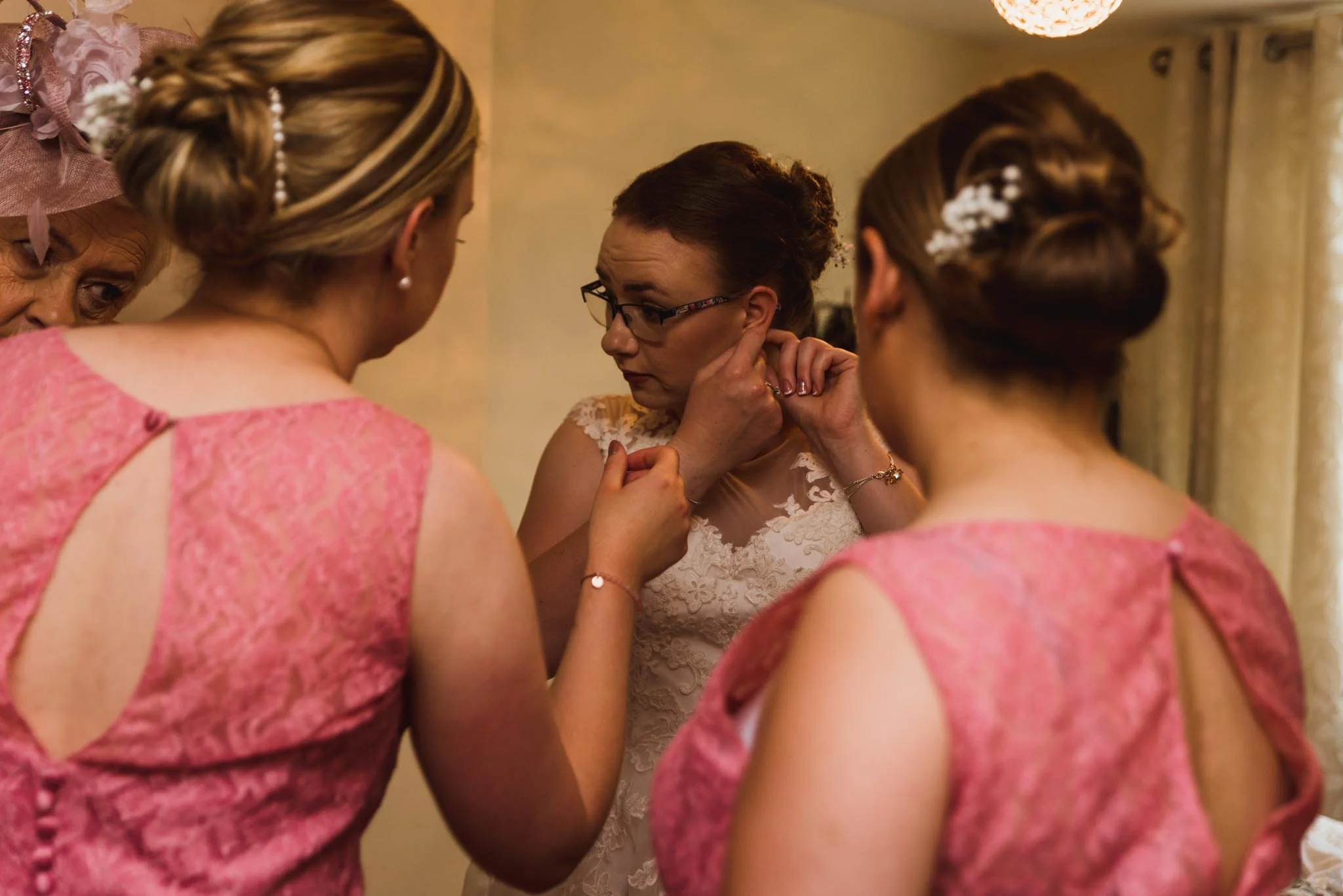 Bride fixing her earring with the bridesmaids.