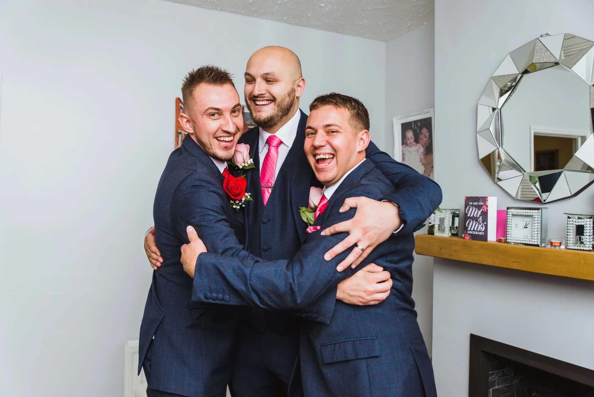 The groom and groomsmen are hugging in the living room.