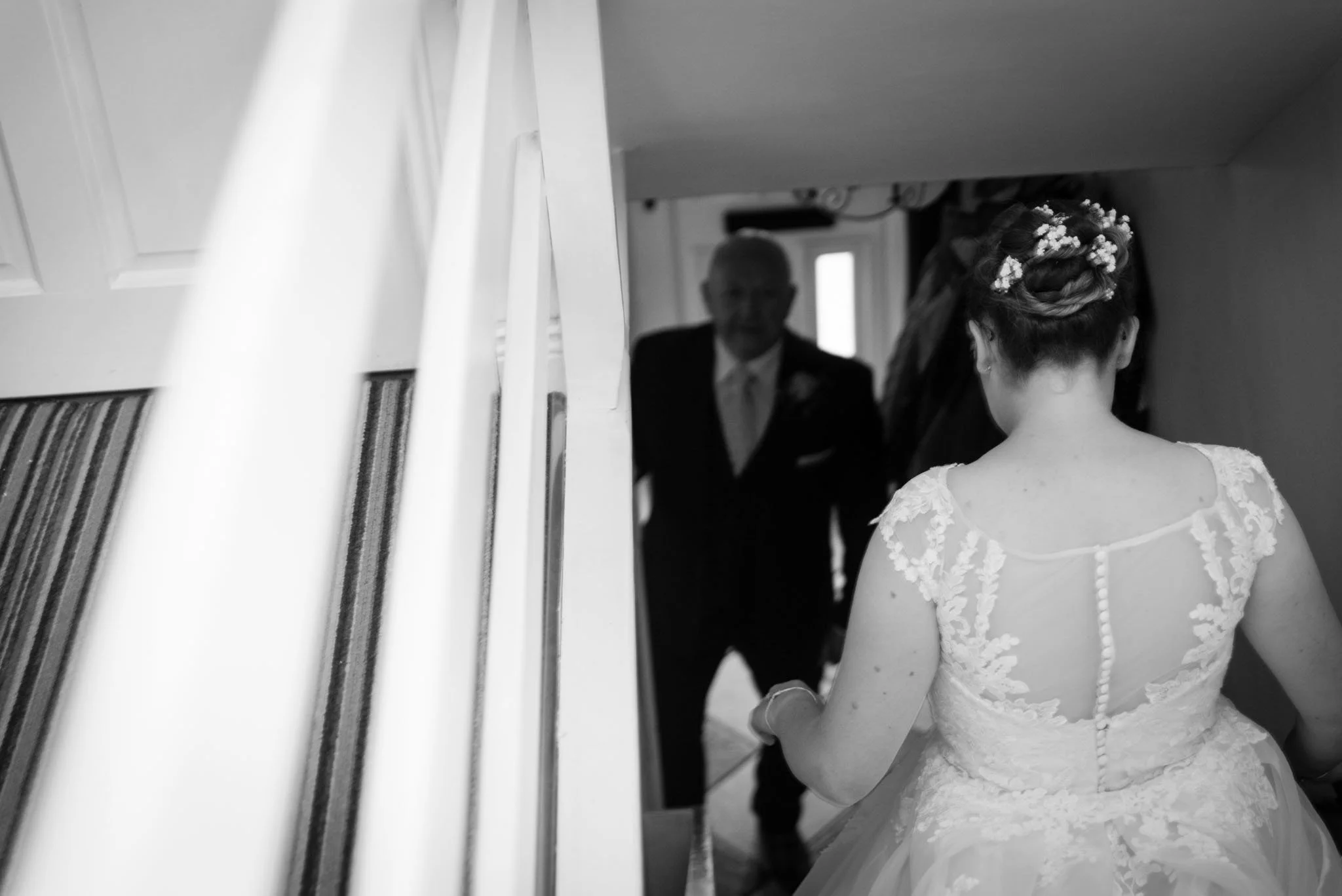 Bride walking down the stairs as father is standing waiting for his daughter for a first look.