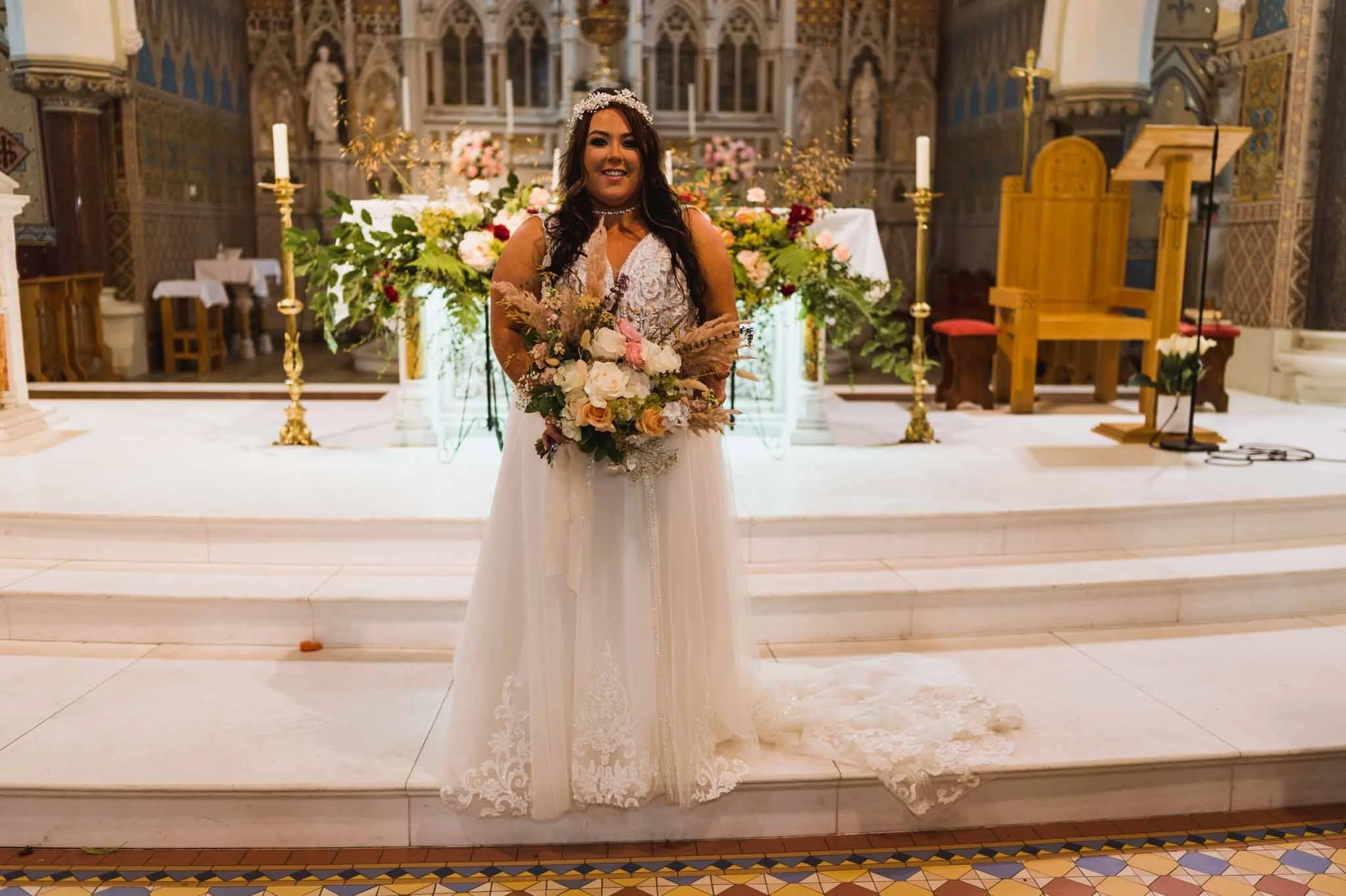 Bride standing holding bouquet for a portrait in front of alter in the church.