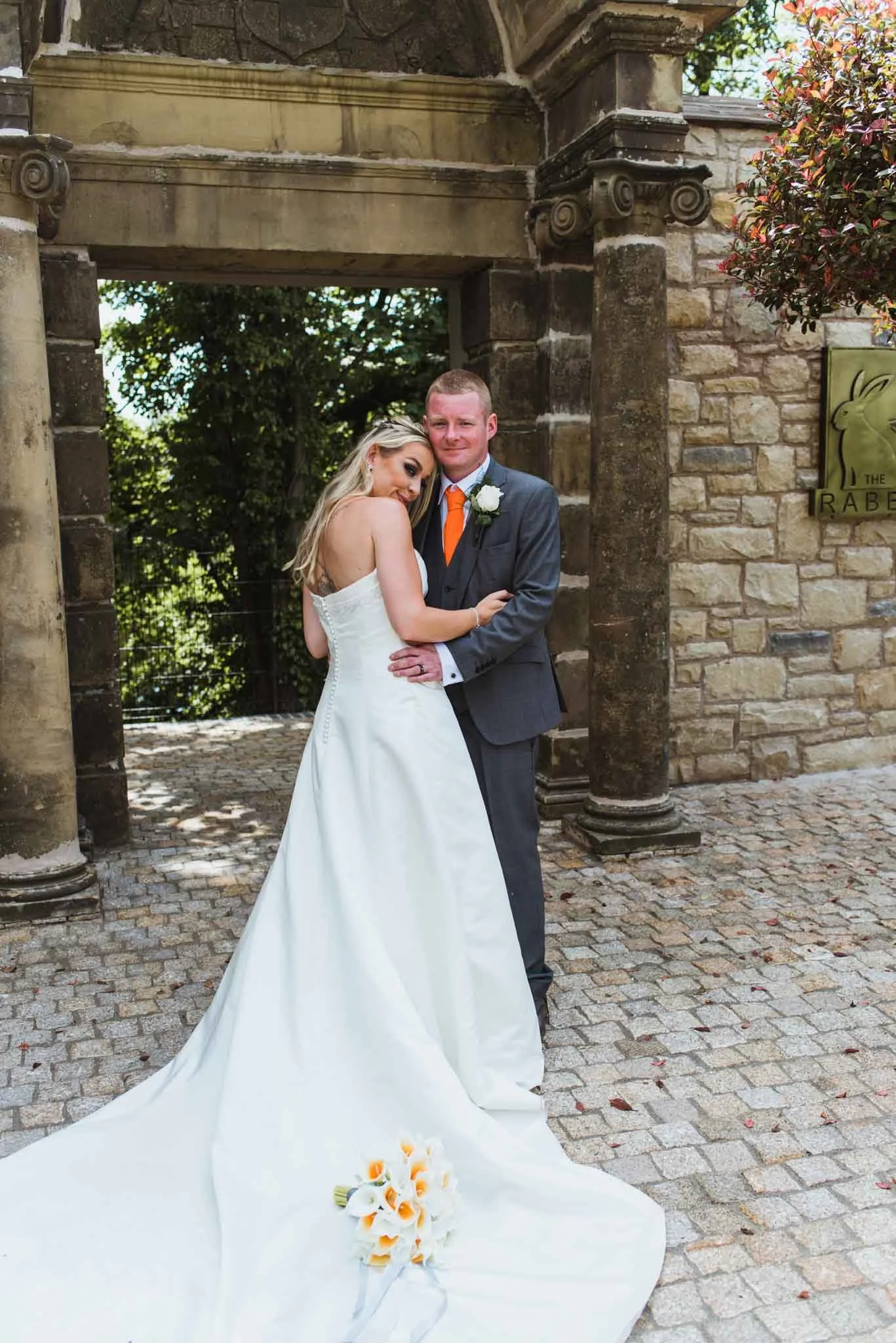 Bride showing dress with bouquet sitting on it, holding onto the groom.