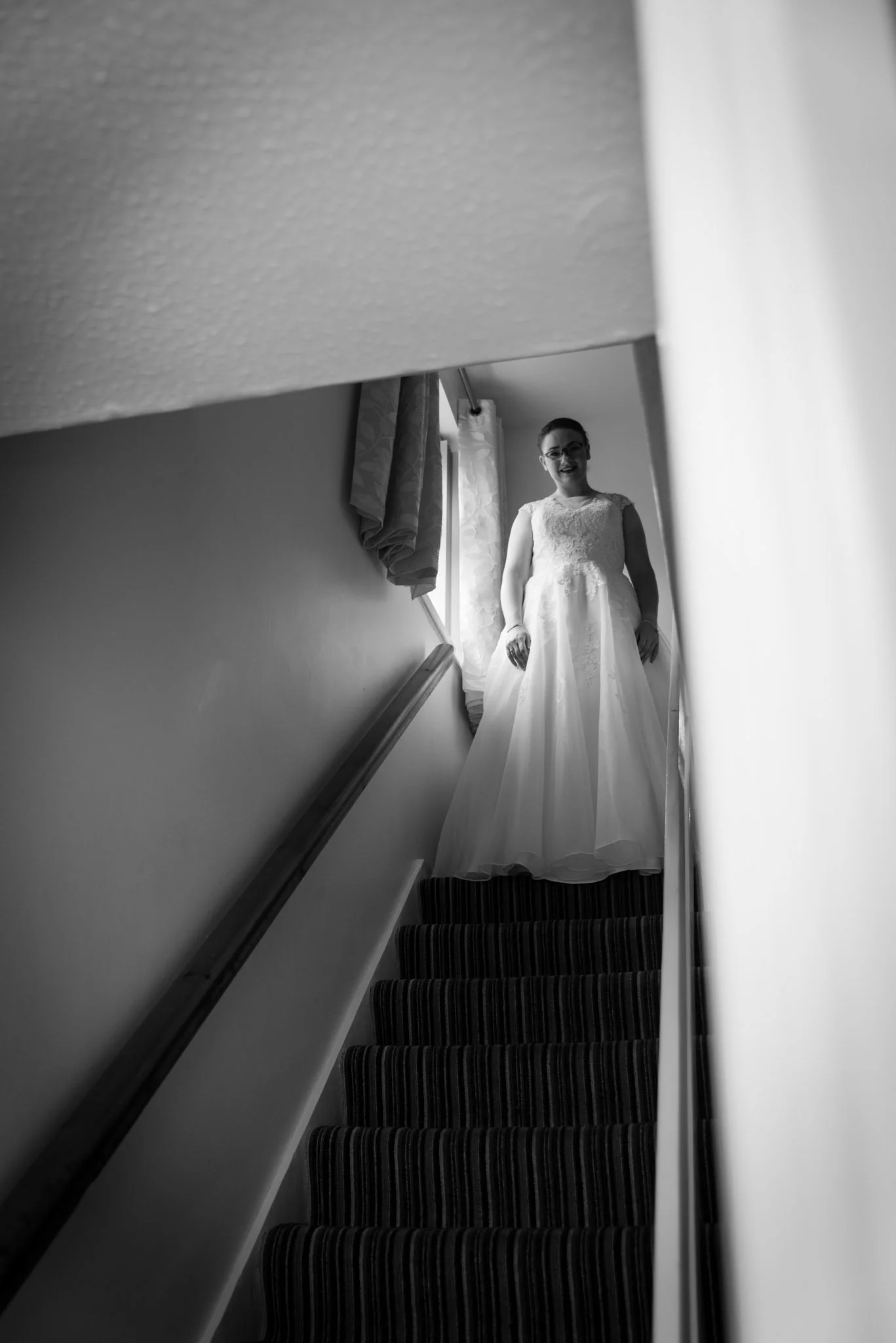 Mono of the bride at the top of stairs looking down.