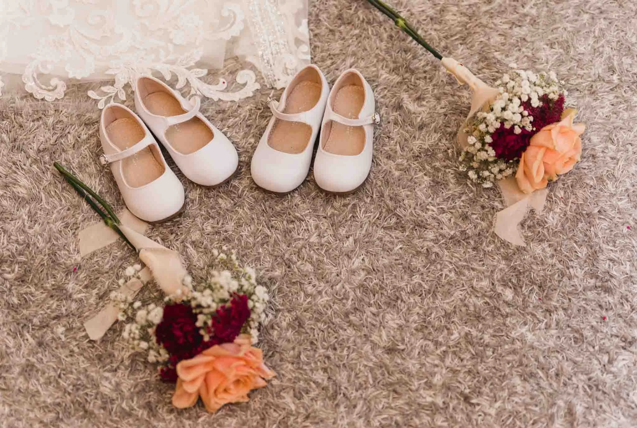 Bridesmaids' shoes beside flowers on the living room carpet.