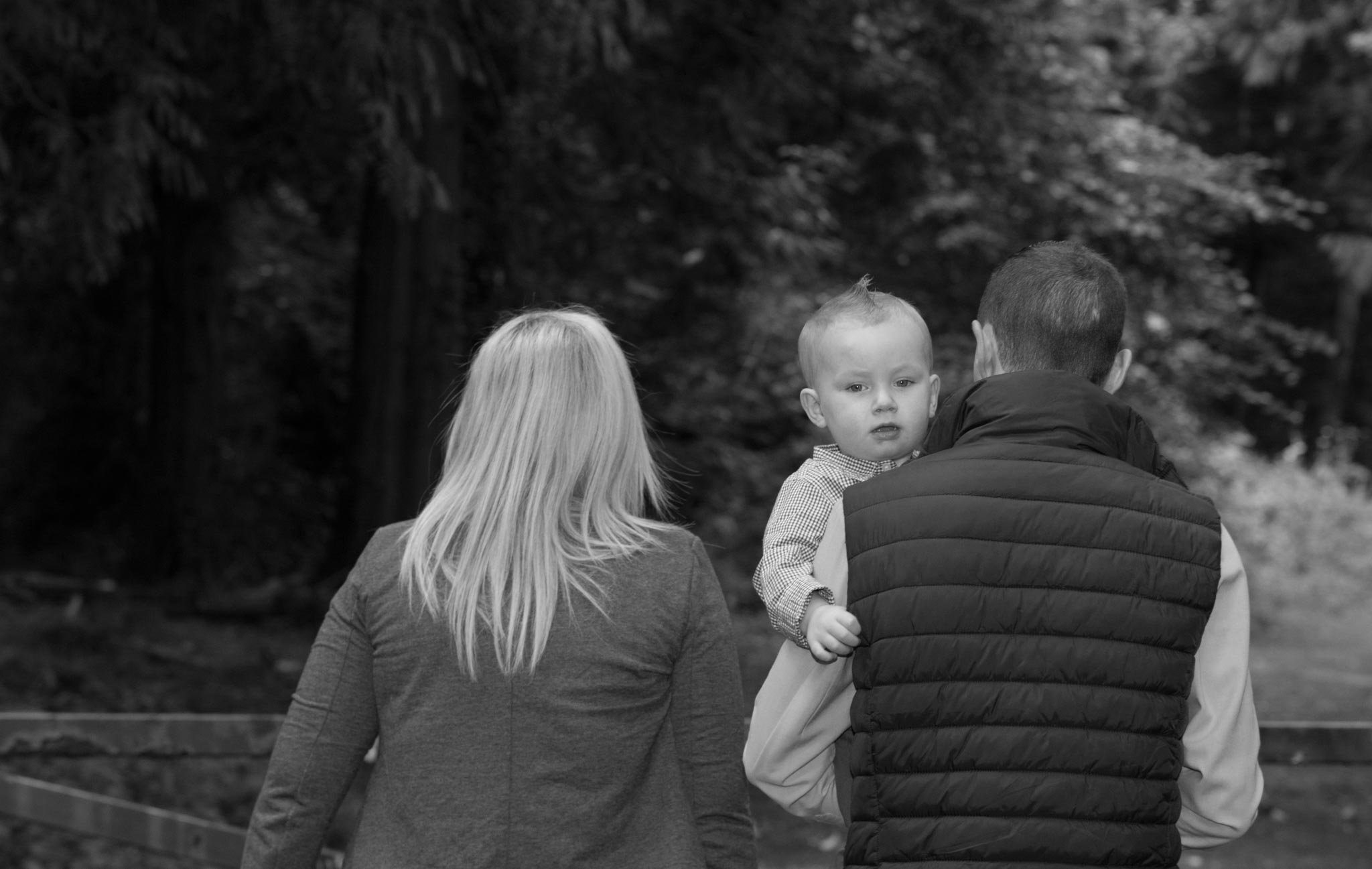 Dad holding son photographed from back in mono.