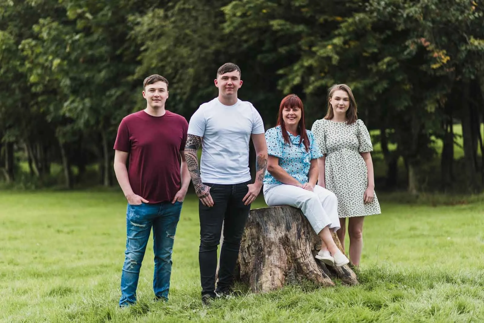 The mother sitting on tree trunk and group children beside her in the park.