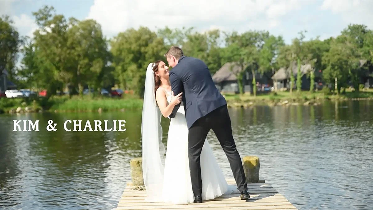 The groom holds the bride in his arms at the jetty.