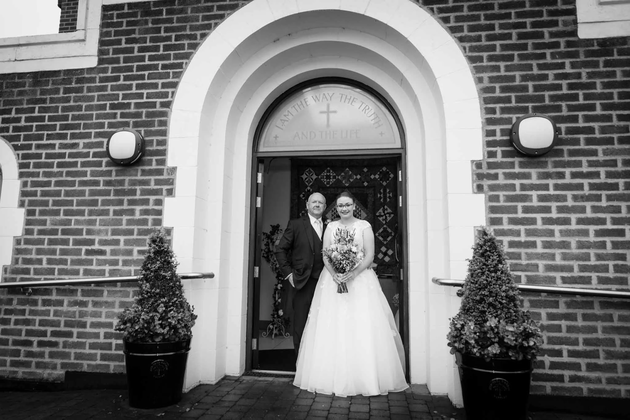 Mono image of the bride with father at the entrance.
