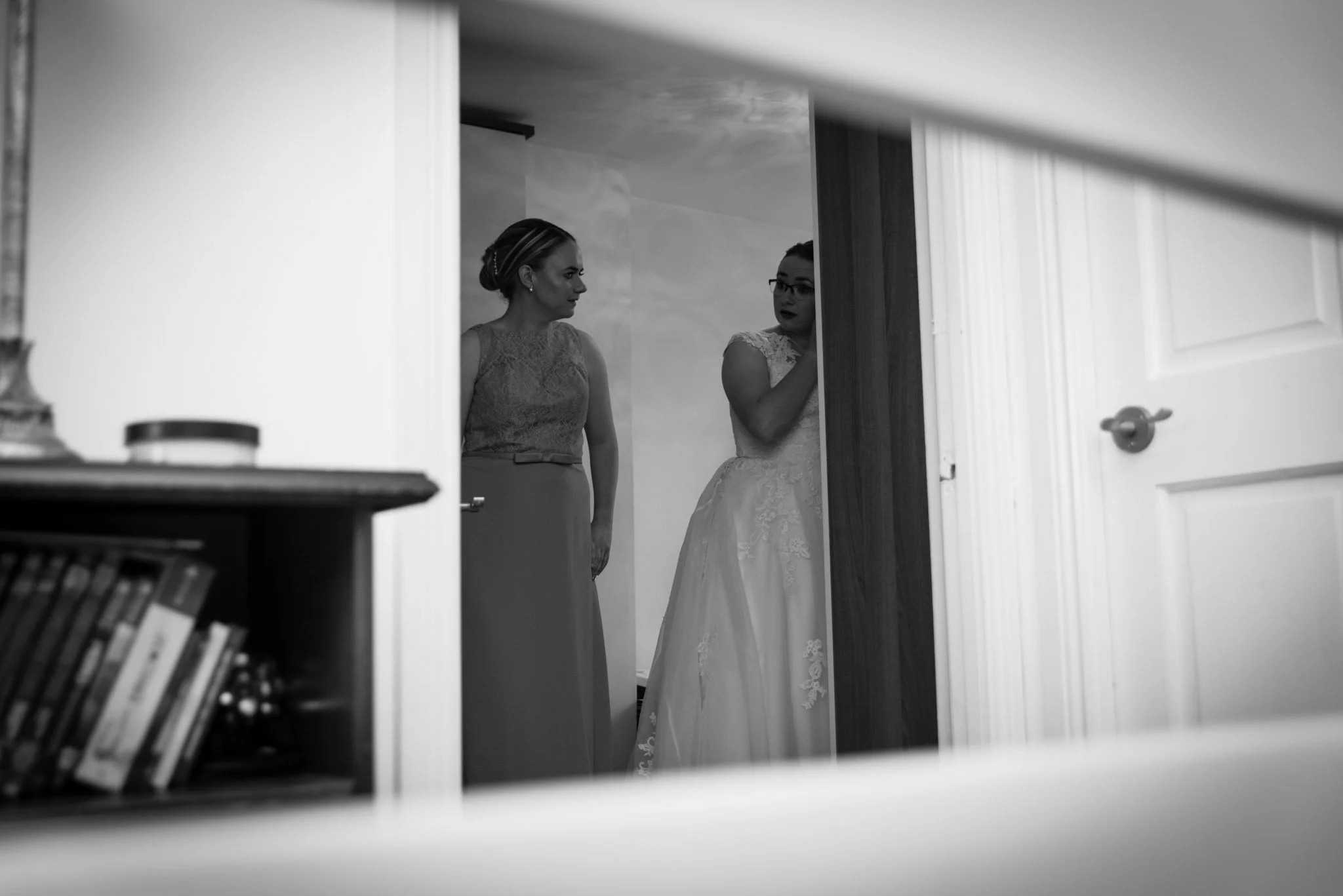 The bride, fixing her earring photographed through the bannister.
