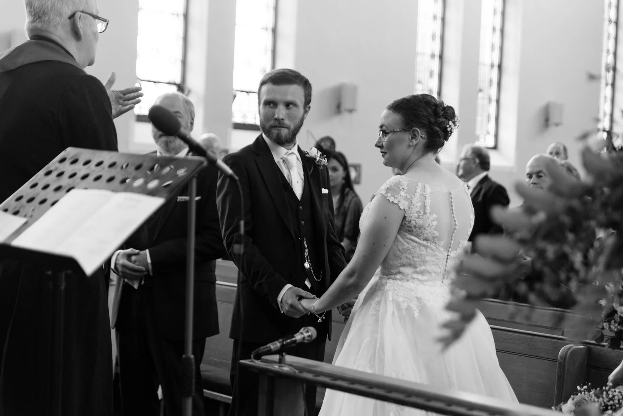Mono picture of the couple holding hands, listening to the minister conducting the ceremony.