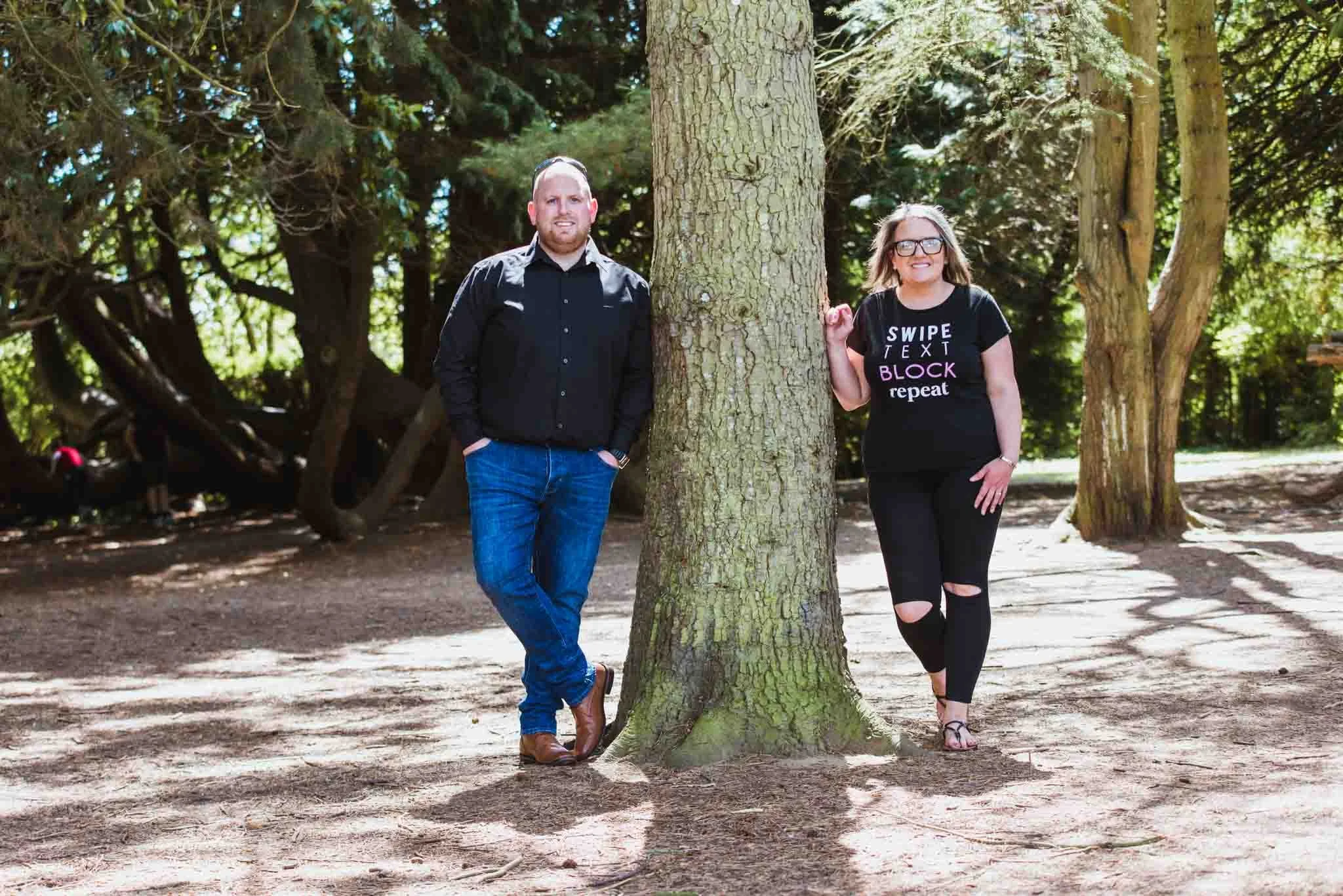 Male and female leaning against side of tree.