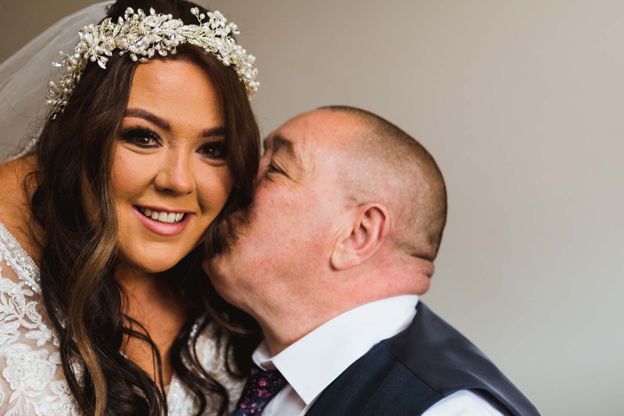 Father kissing his daughter, the bride, on the cheek.