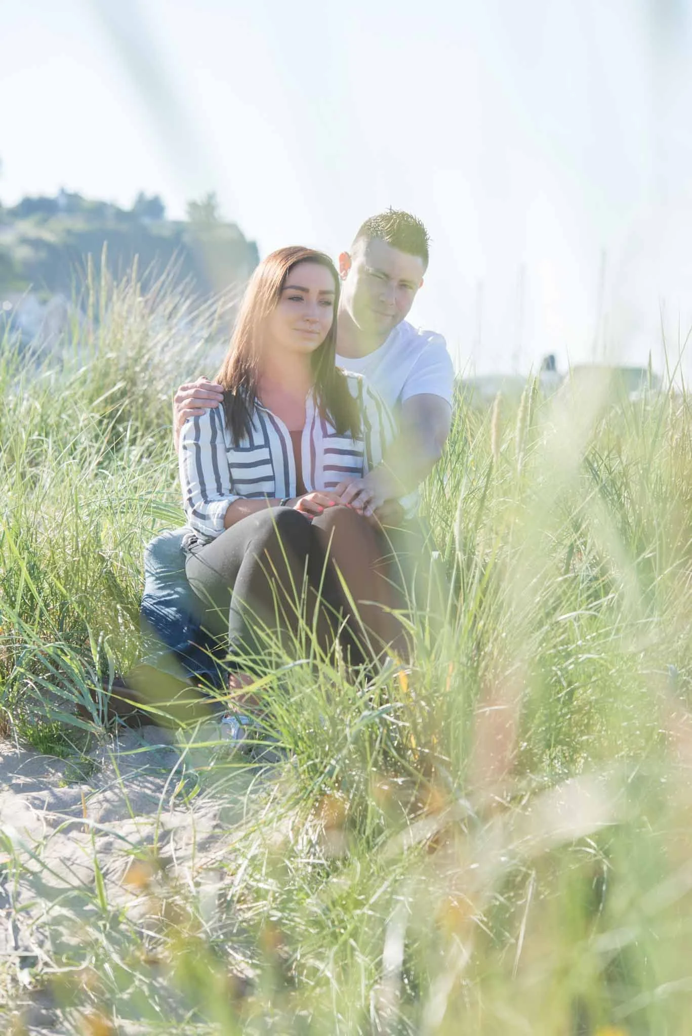 A couple sitting at the beach along the north coast with plenty of beachgrass around them.