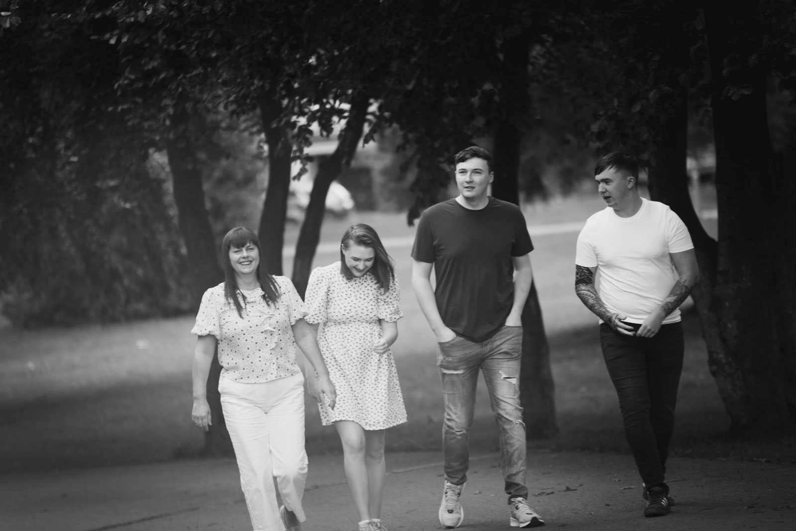 Mono image of the family walking together with plenty of trees behind them.