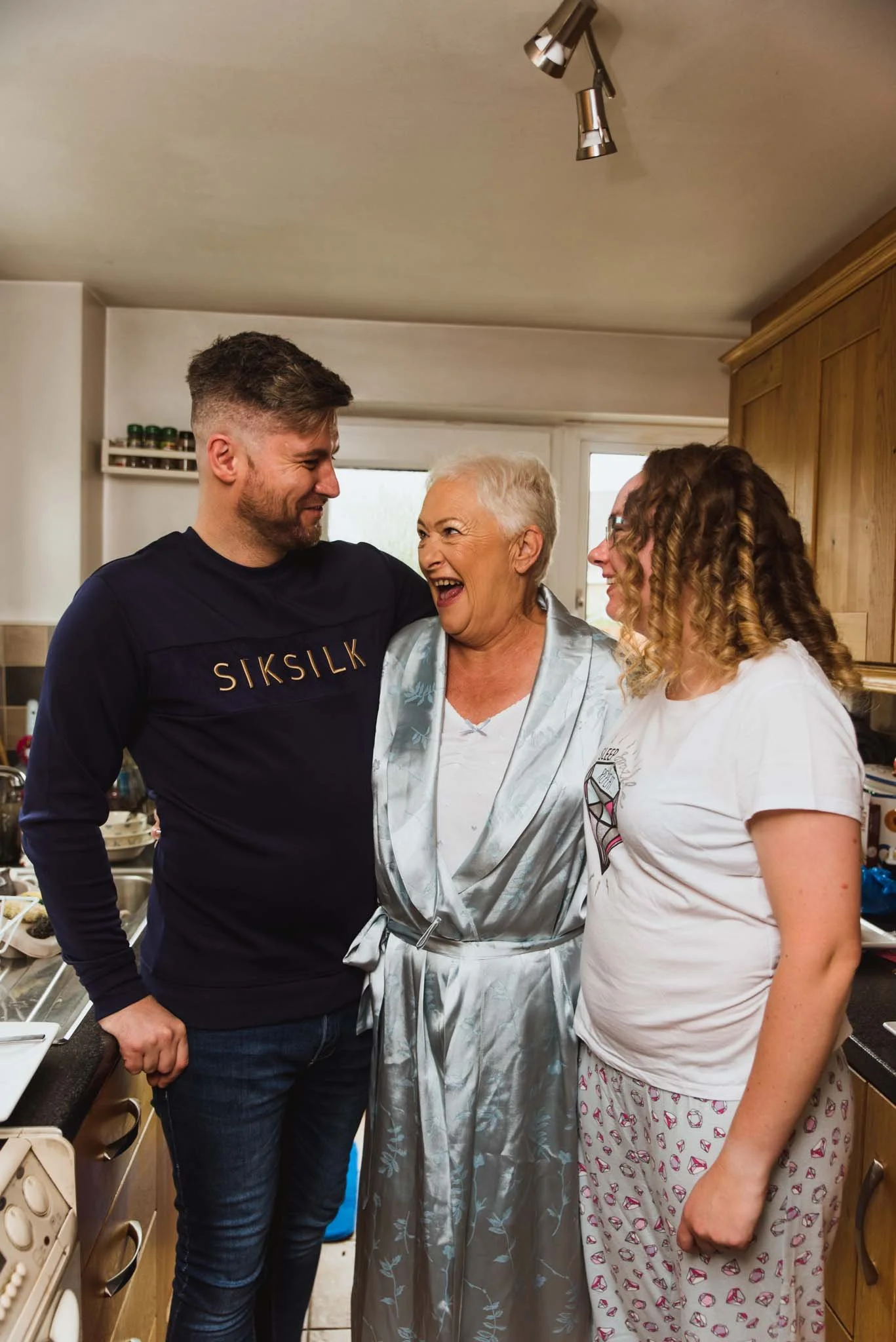 The bride, with brother and mother in the kitchen laughing.