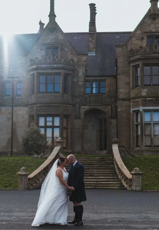 A married couple touching heads outside the castle venue.