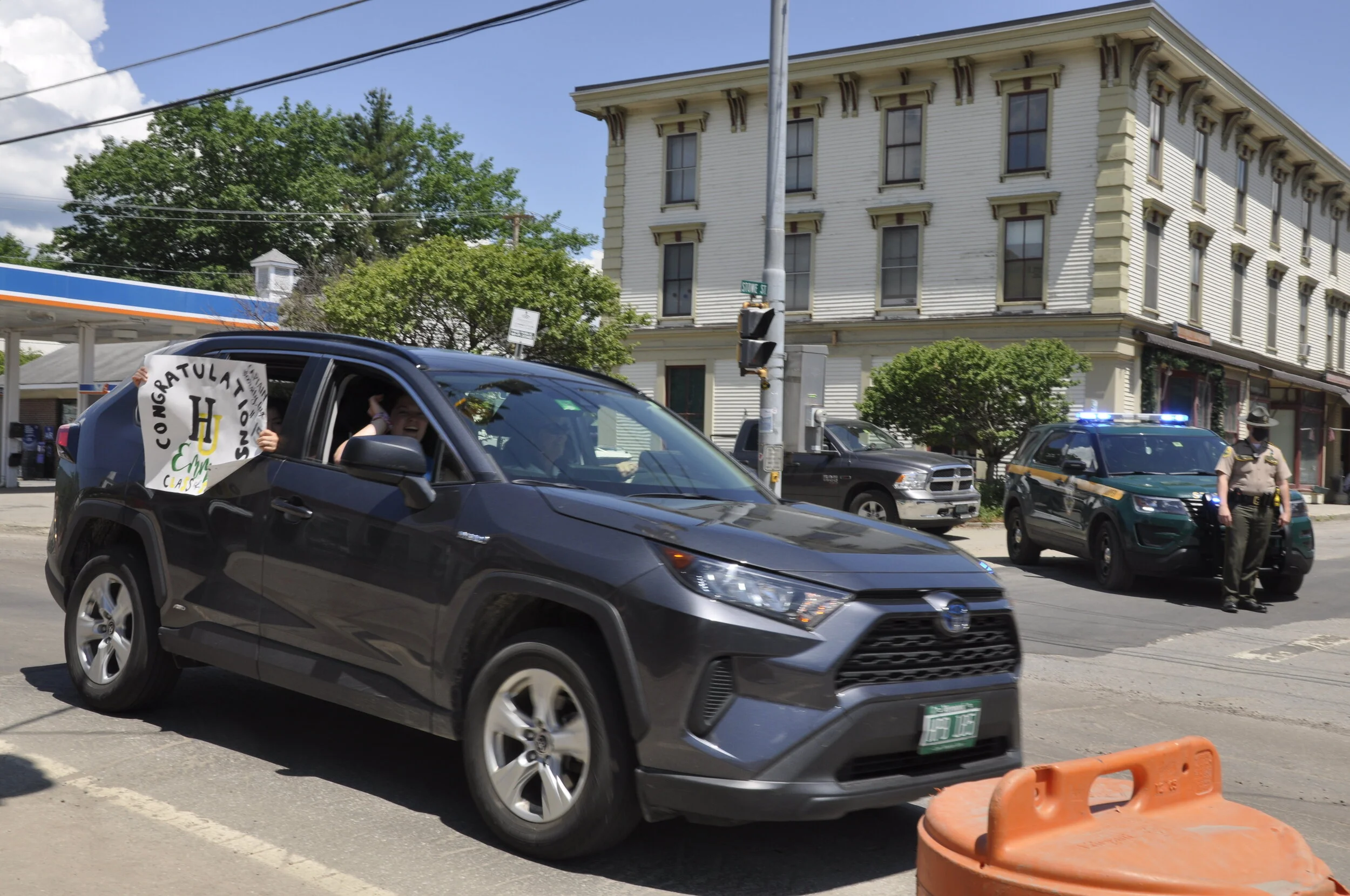   One of three state troopers stands watch wearing a face mask at the intersection of Stowe and Main streets as the parade passes through Waterbury. Photo by Lisa Scagliotti.  