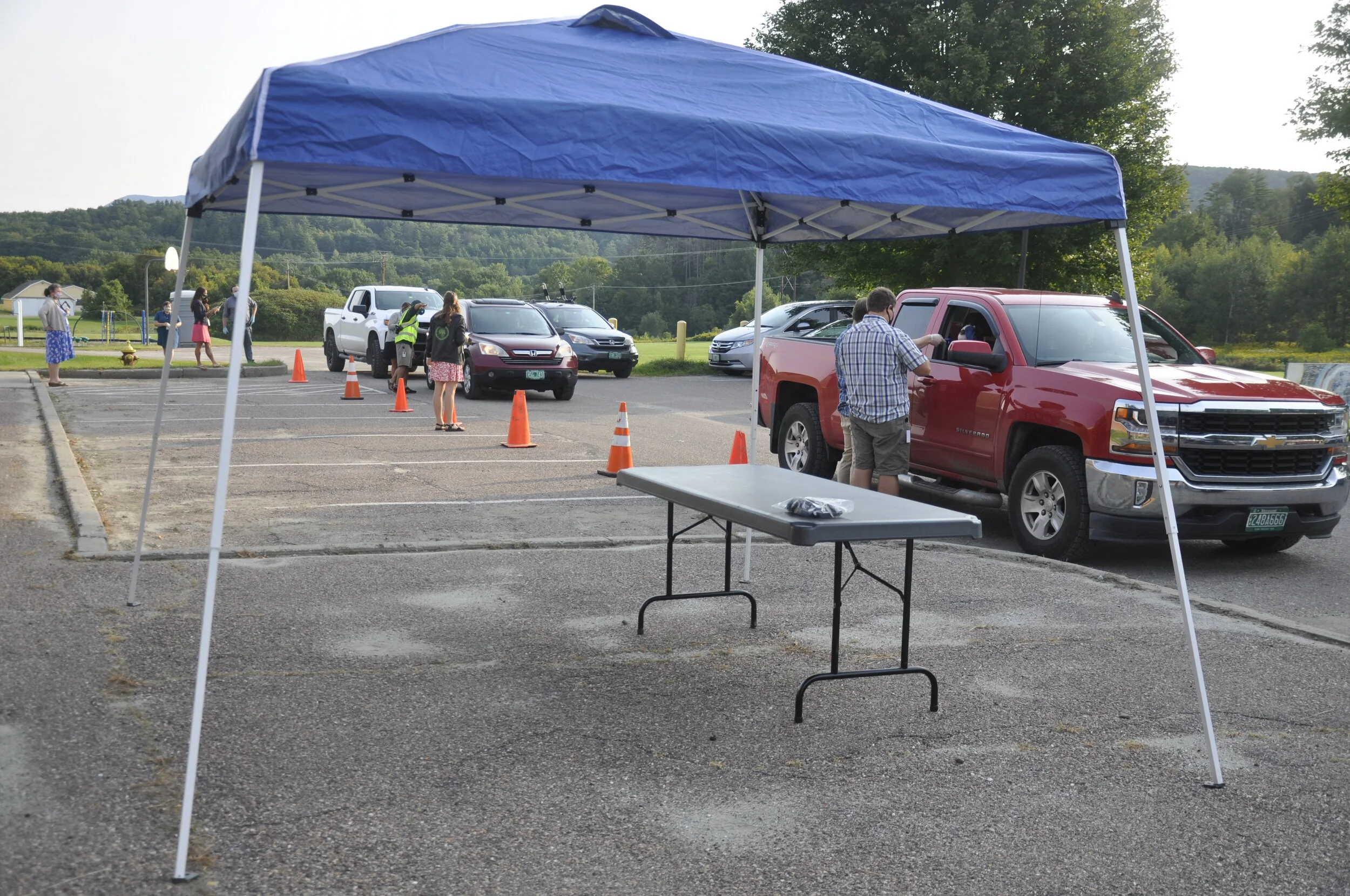   Staff work in pairs along the curbside check-in near the gym entrance. The end of the line winds around Crossett Brook about 45 minutes after arrivals began. Photo by Lisa Scagliotti.  