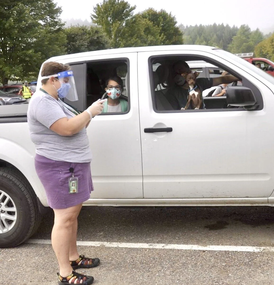  Music teacher Molly Dubois screens backseat fifth grade passenger Lily Weigand while dad Scott and dog Kona look on. Photo by Lisa Scagliotti.  