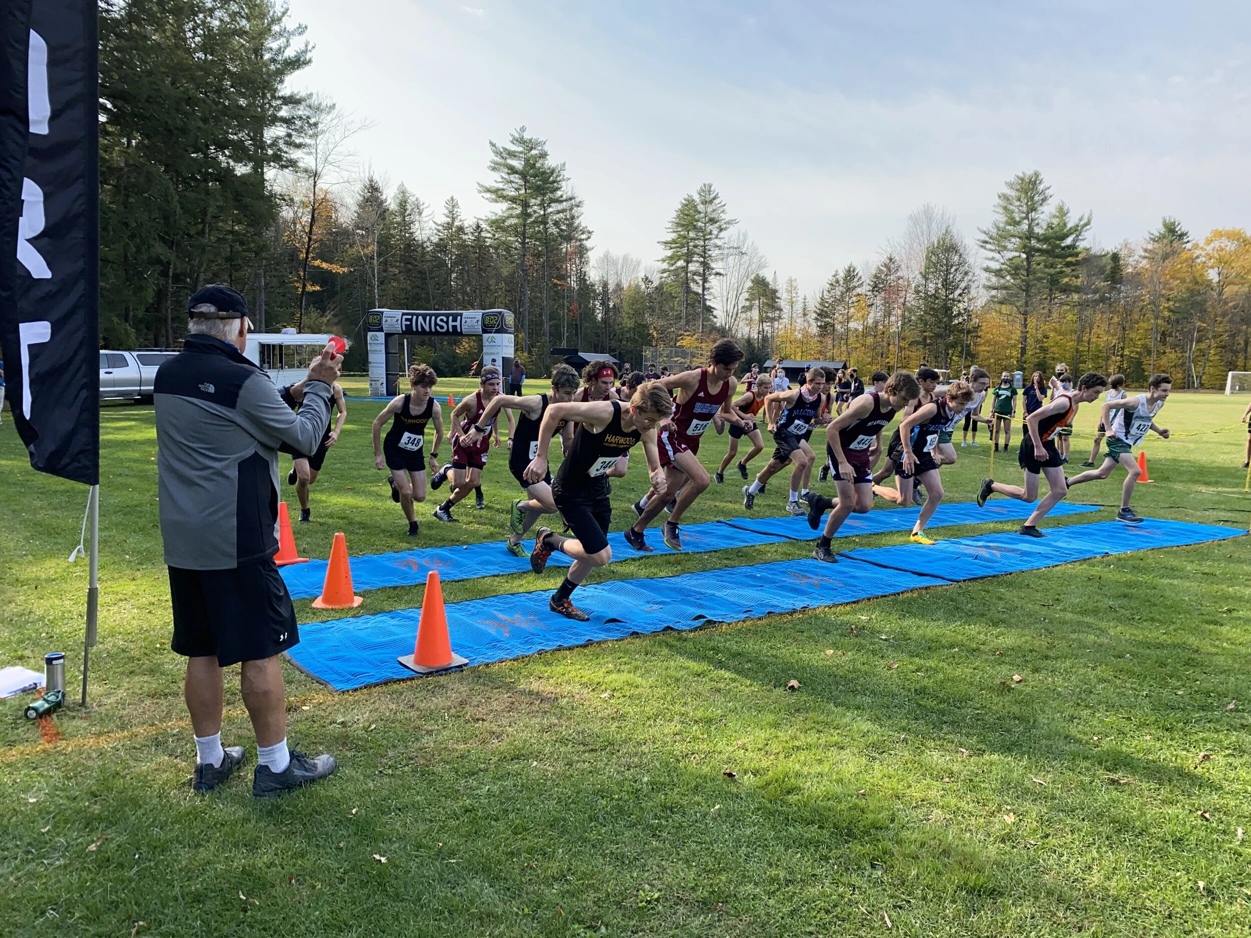   Harwood Coach John Kerrigan sounds the horn for the start of Wave 2 in the Boys’ Varsity race. Photo courtesy Susan Cummiskey.  