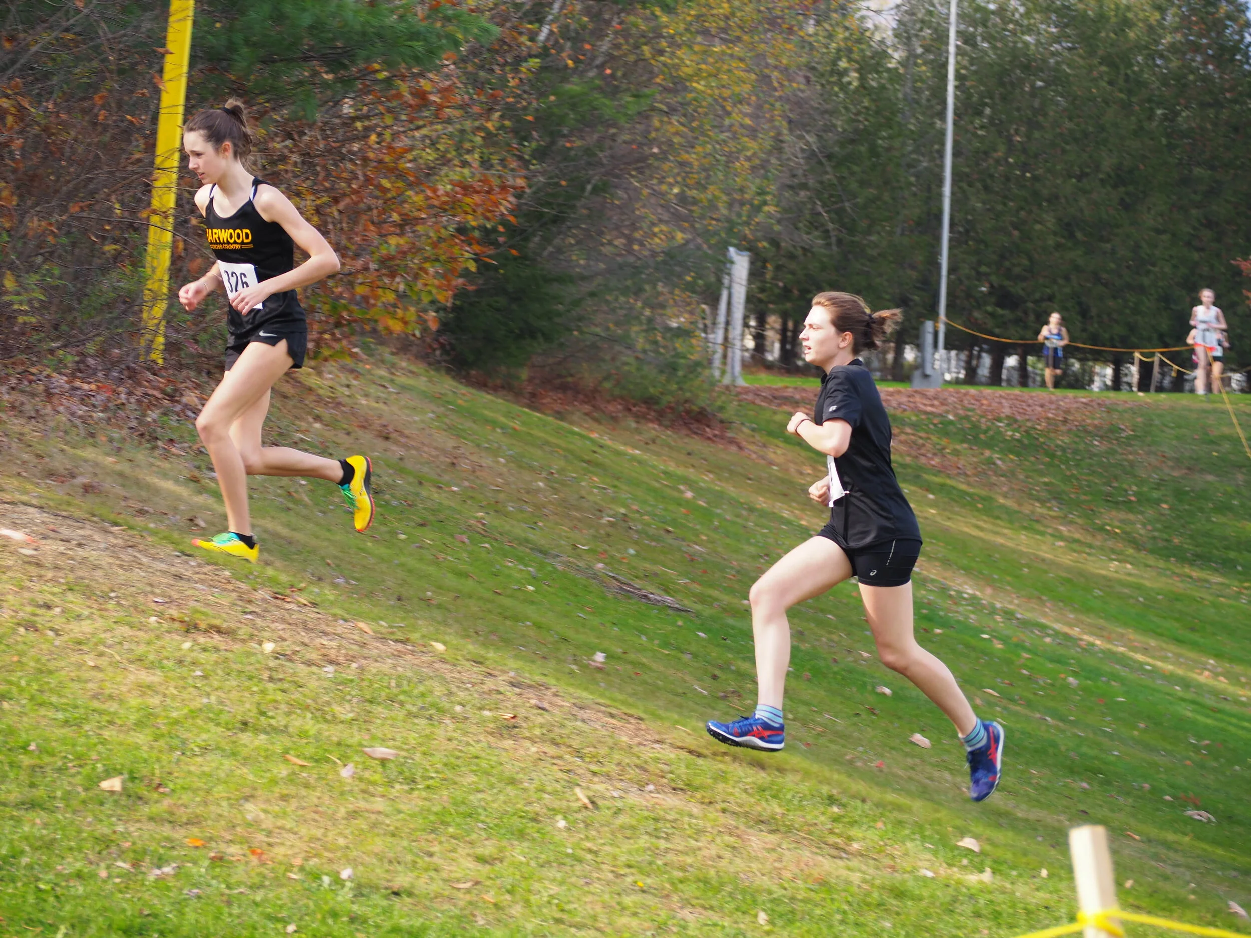   JV runners McKenna Paxman for Harwood and Laura Martinez from Montpelier's Pacem School on a climb. Photo by Ann Zetterstrom.  