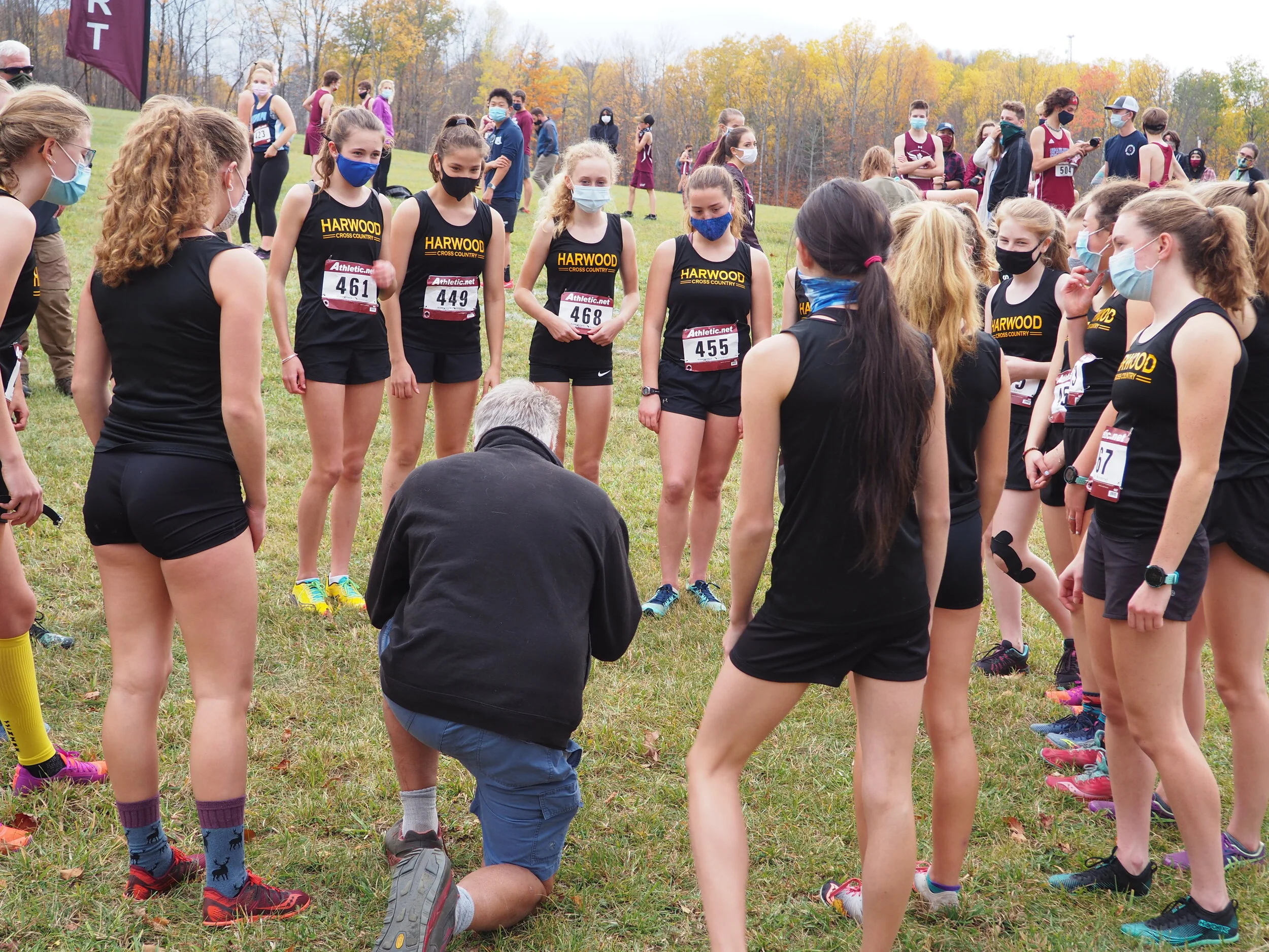   Head Coach John Kerrigan huddles with the Harwood Girls X-C squad. The girls defend their title at Saturday's state championship meet. Photo courtesy the Zetterstrom family.  