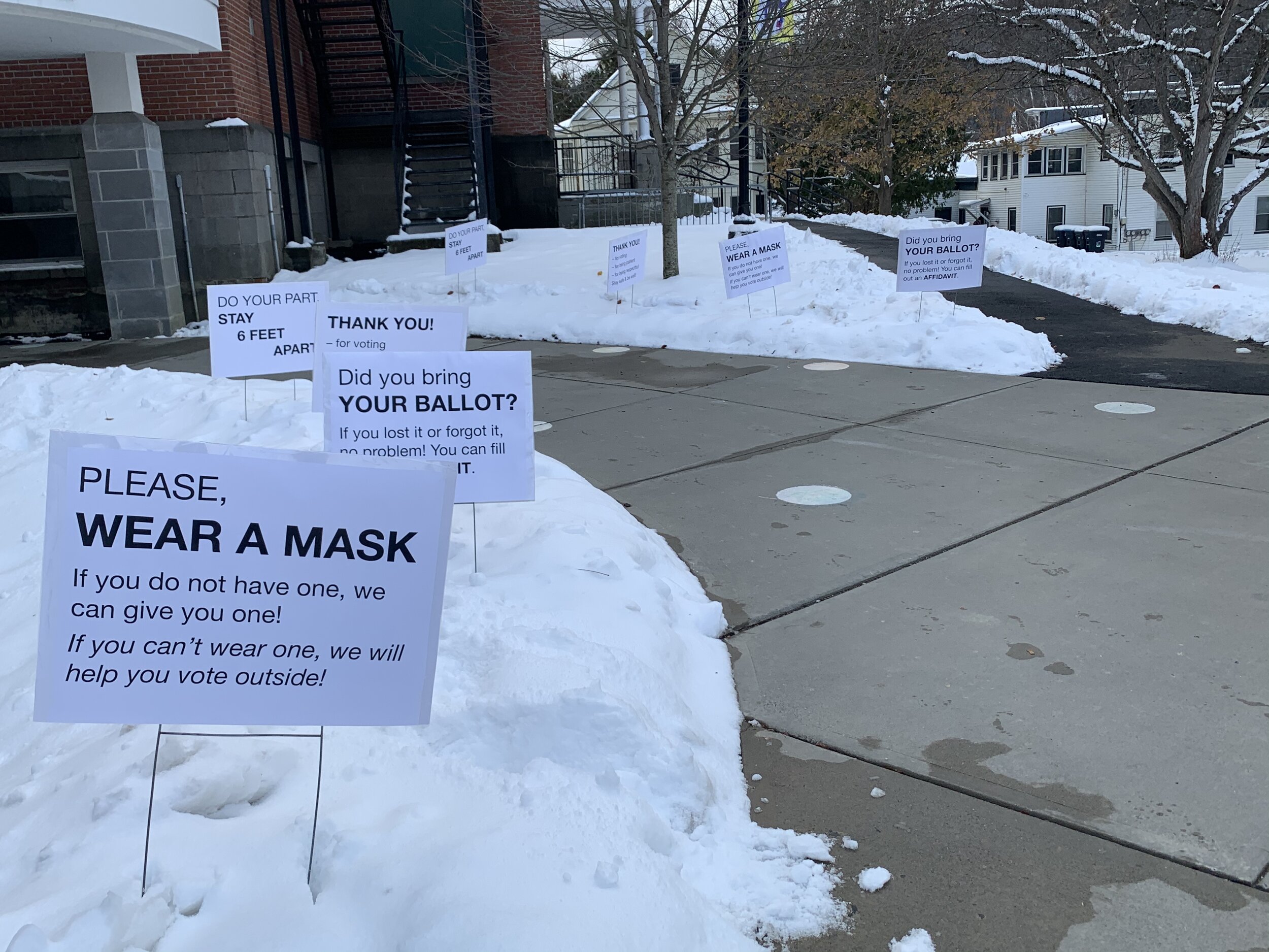   Impacts of COVID-19 ripple through election day with reminders to distance and wear masks, etc. popping out of the fresh snowbanks outside Thatcher Brook Primary School Tuesday. Photo by Lisa Scagliotti.  