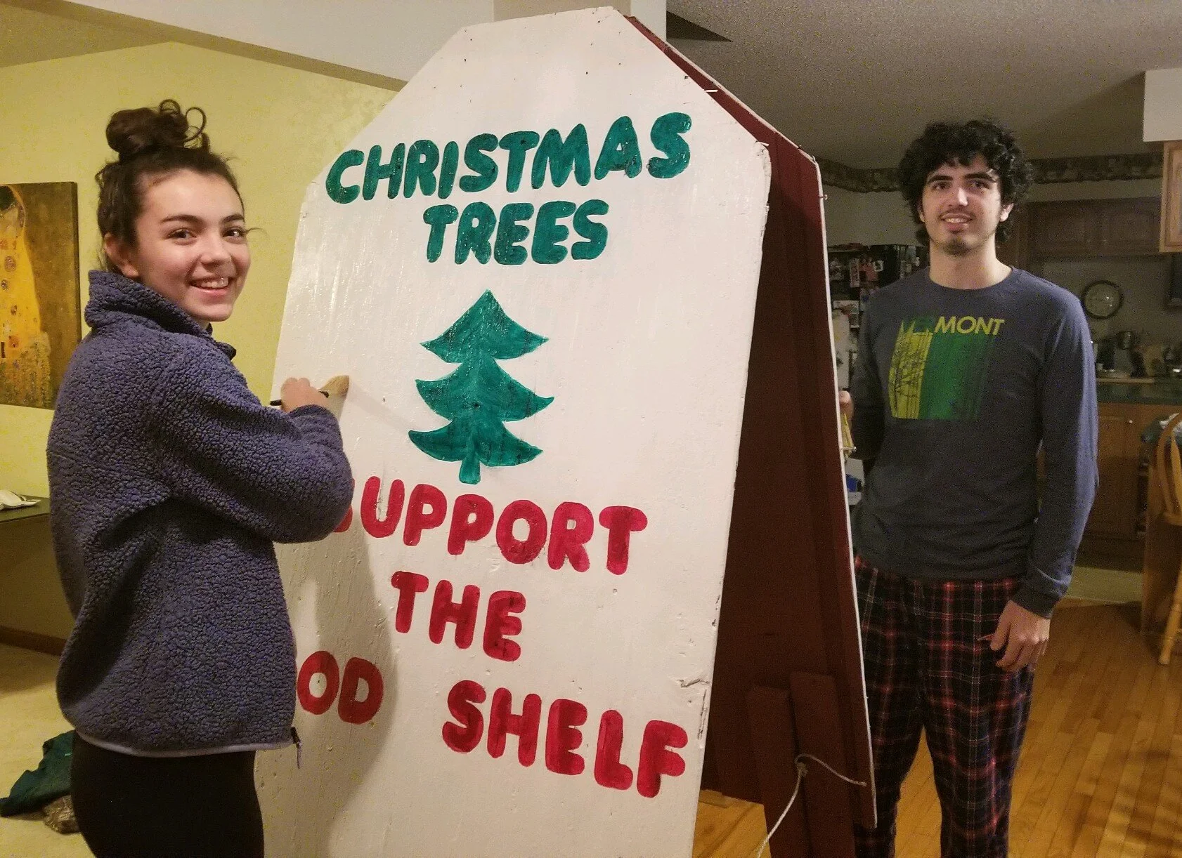   Ashley and Andrew Proteau spruce up the vintage sign with fresh paint. Their family took on rehabbing the familiar sight that beckons people to the church yard each year. Photo by Leslie Proteau.  