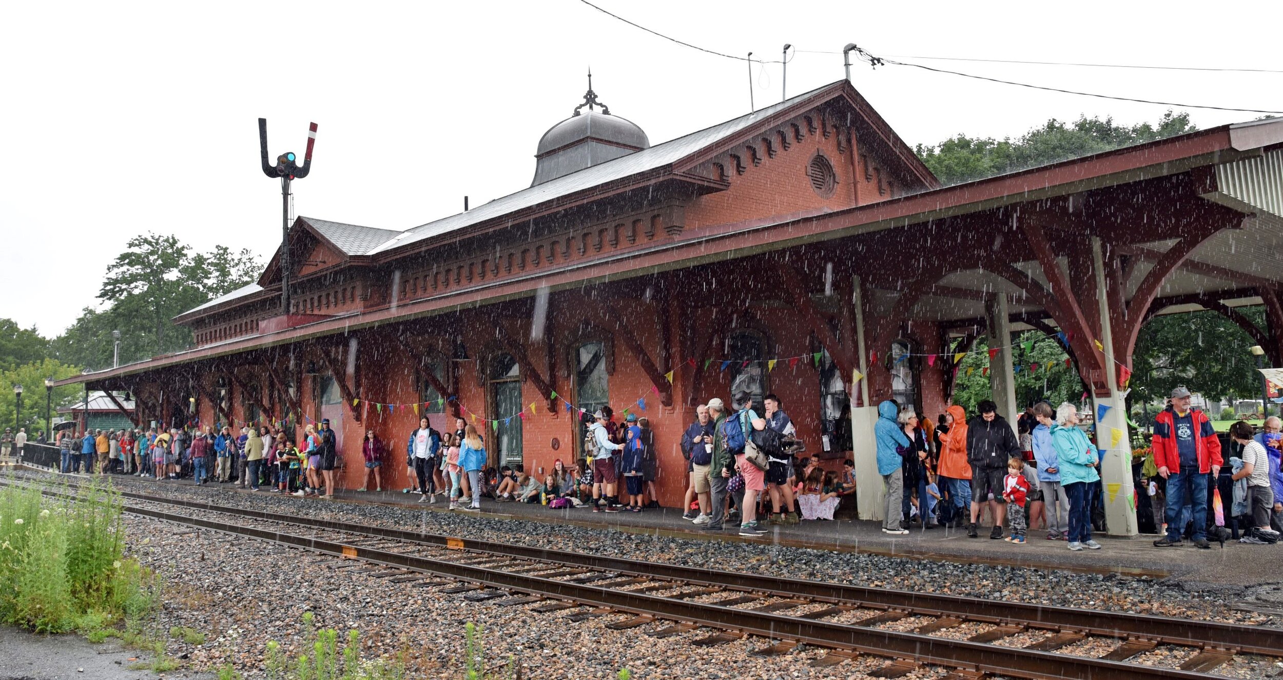   The crowd awaiting Amtrak in Waterbury takes shelter under the train station's eaves and on its covered deck Monday morning. Photo by Gordon Miller  