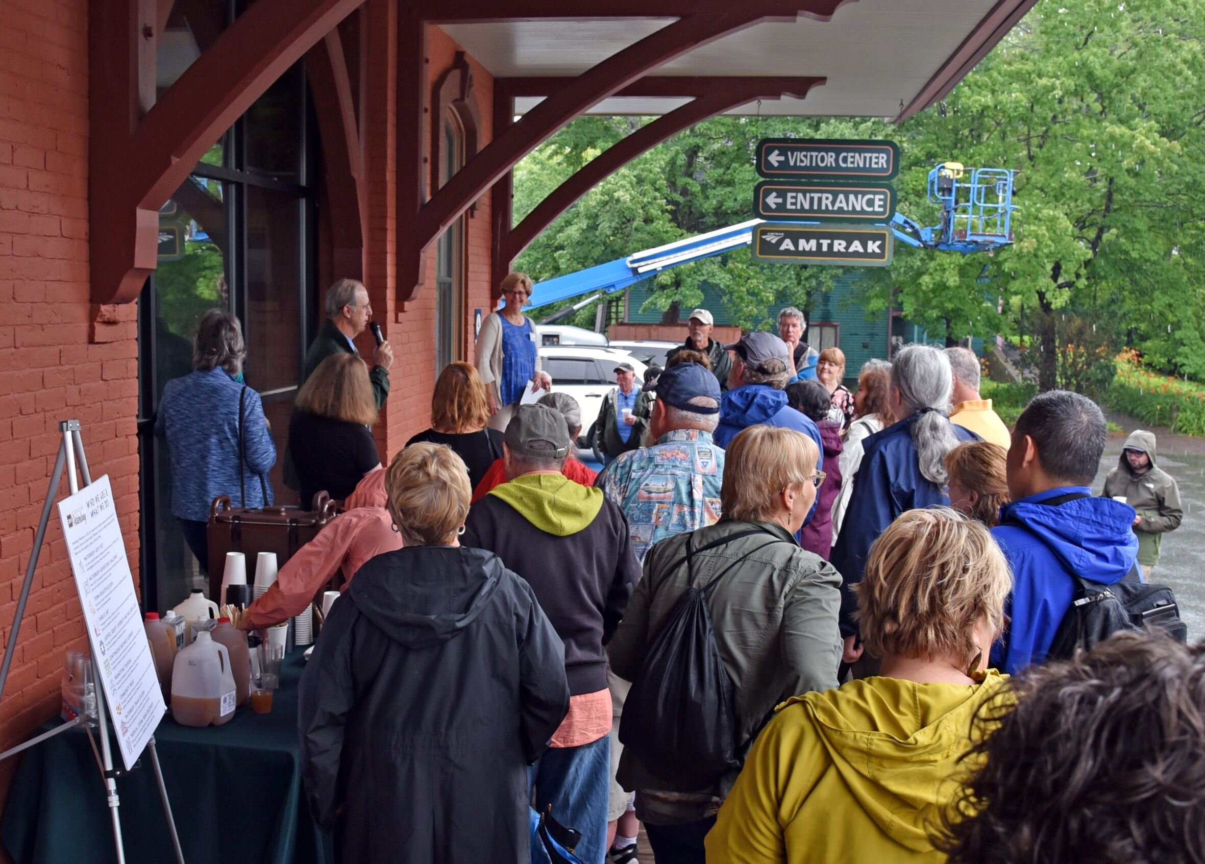   Municipal Manager Bill Shepeluk addresses the crowd before the train arrives. Members of the public filled the train station's covered porch to take cover from the rain and get closer to hear. Photo by Lisa Scagliotti  