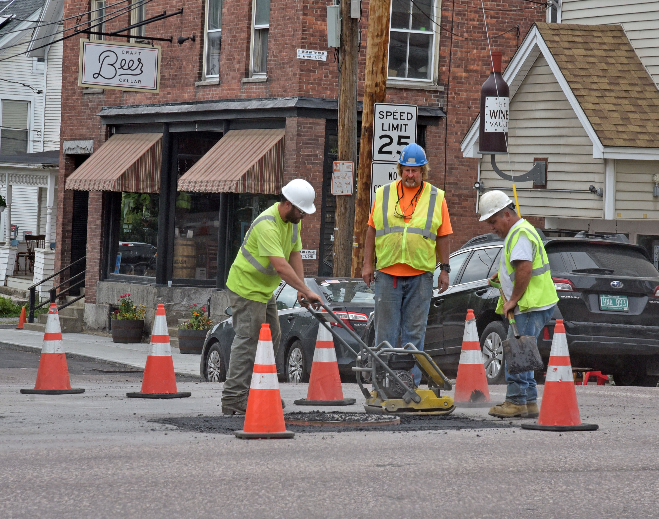   Workers prep areas around manholes and underground utility accesses ahead of final paving. Photo by Gordon Miller  