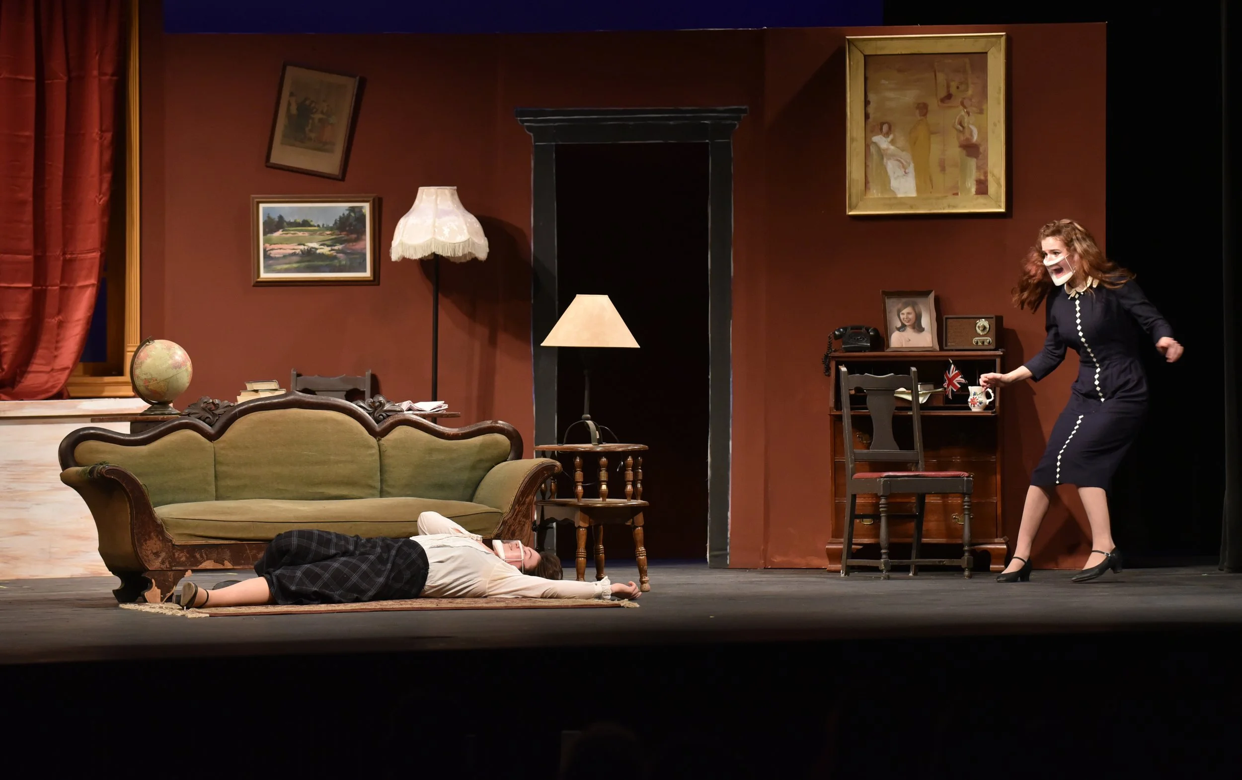   From behind the window curtain, Christopher Wren (played by Tarin Askew) eavesdrops on the Ralstons (Zoe Blackman and Arianna Clark). Photo by Gordon Miller  