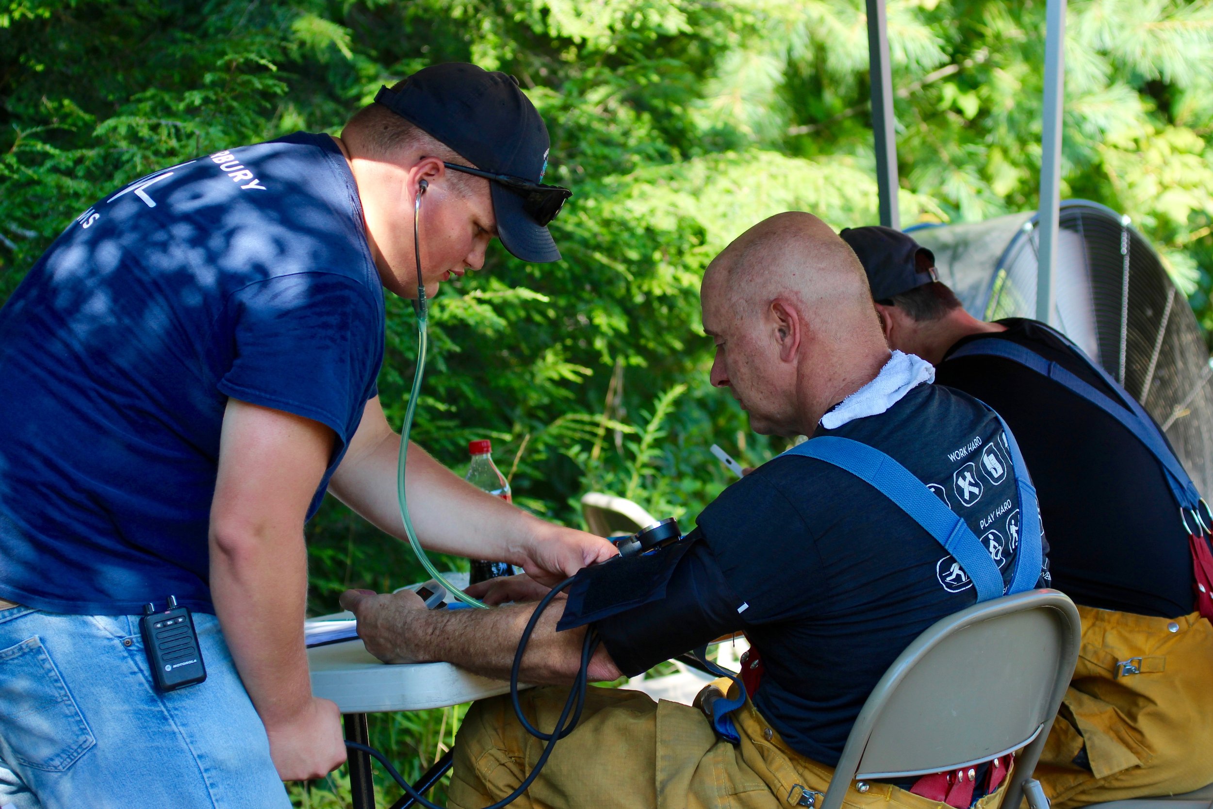   Waterbury Ambulance EMT Kaden Giroux checks firefighter John Pitrowiski’s vitals in-between rotations. Photo by René Morse  
