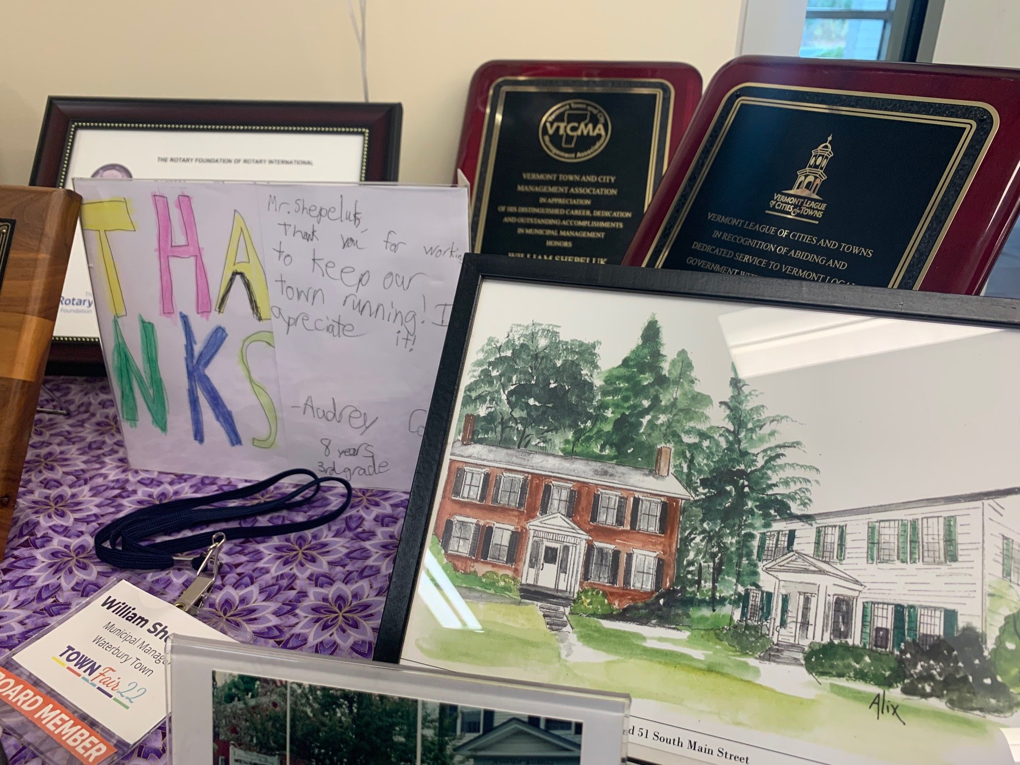  A collection of awards, souvenirs and mementos — including a child’s thank you note and a watercolor of the former town offices — from Shepeluk’s years as municipal manager is displayed on a side table. Photo by Lisa Scagliotti 