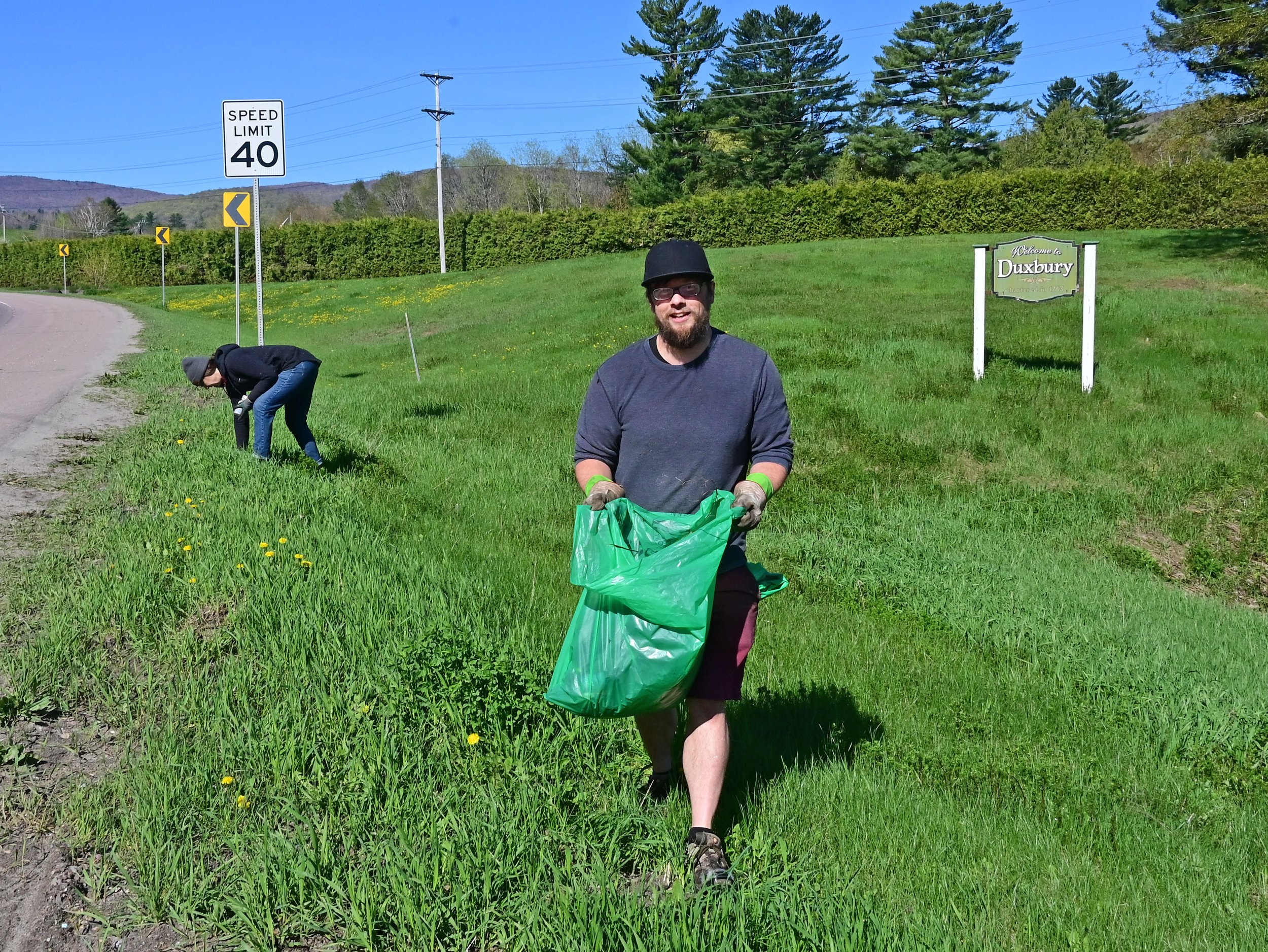  Keith and DeAnna Romstead find trash in the grass along Rt. 100 at the Welcome to Duxbury sign. Photo by Gordon Miller  
