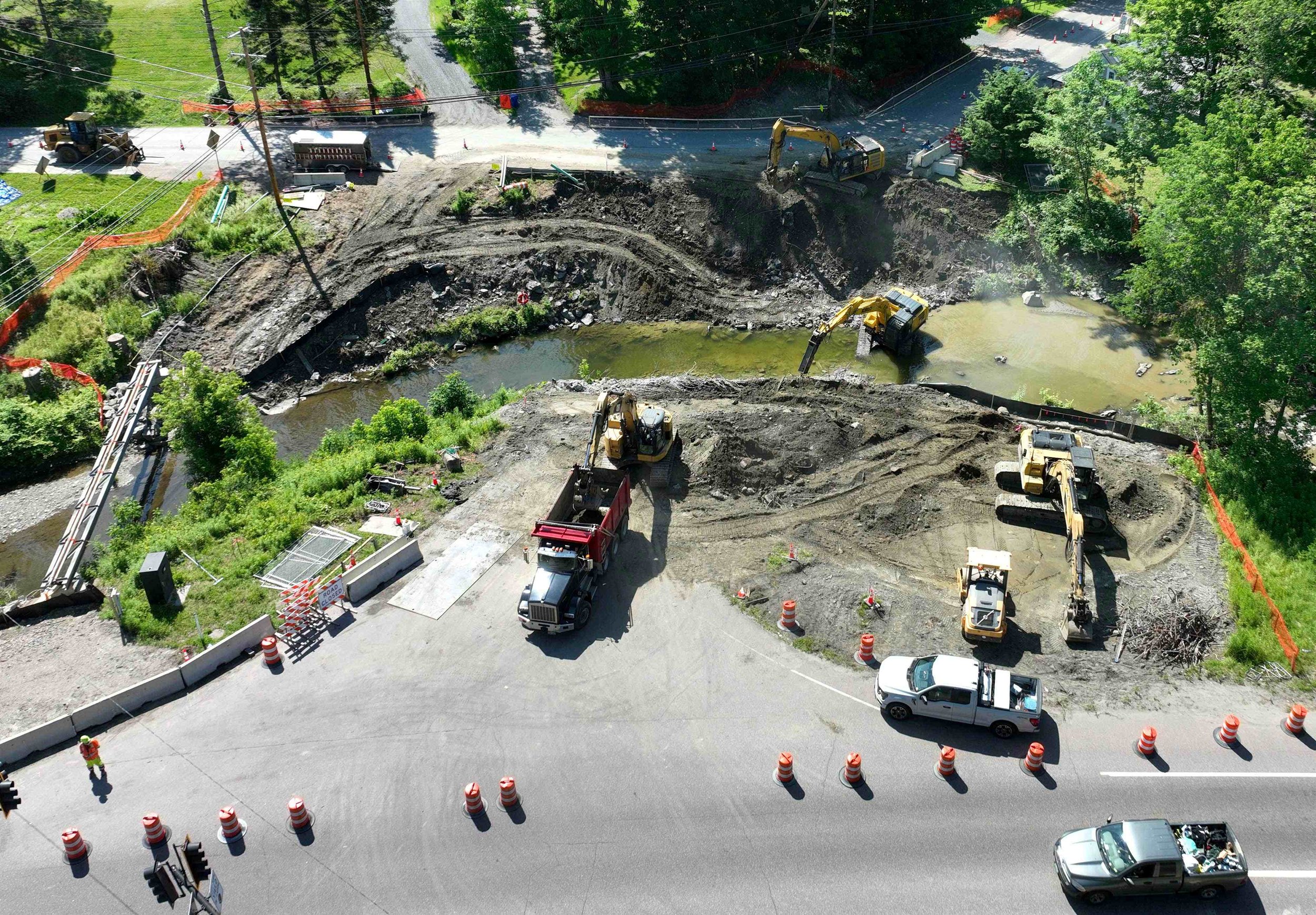 This drone shot shows the bridge site with Rt. 100 at the bottom, Lincoln Street at the top. A temporary sewer line straddles the brook on the left. Photo by Gordon Miller