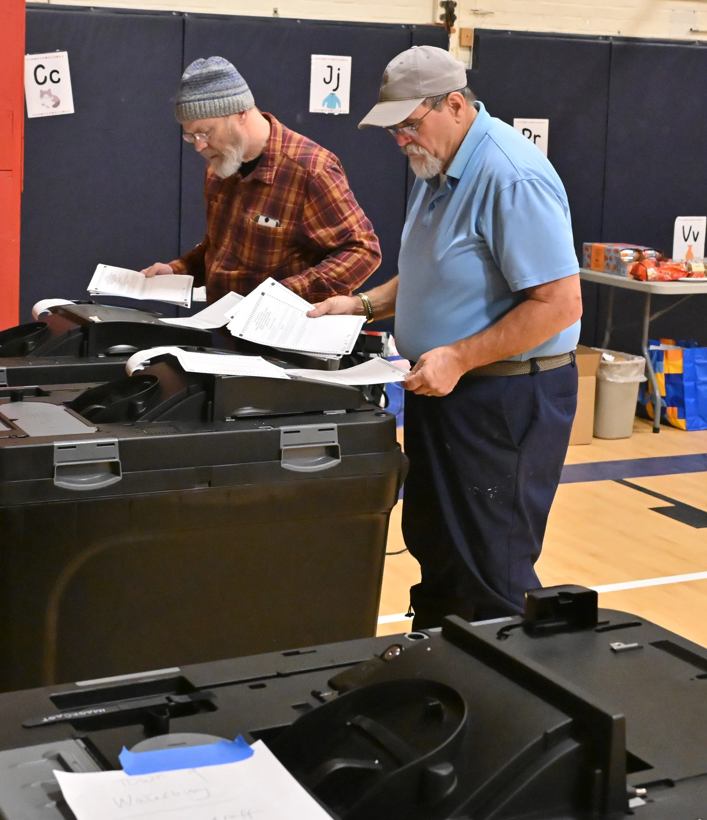   Duxbury elections officials Dan Cardozo and Mo Lavanway feed school district ballots into the tabulator machines. Photo by Gordon Miller  